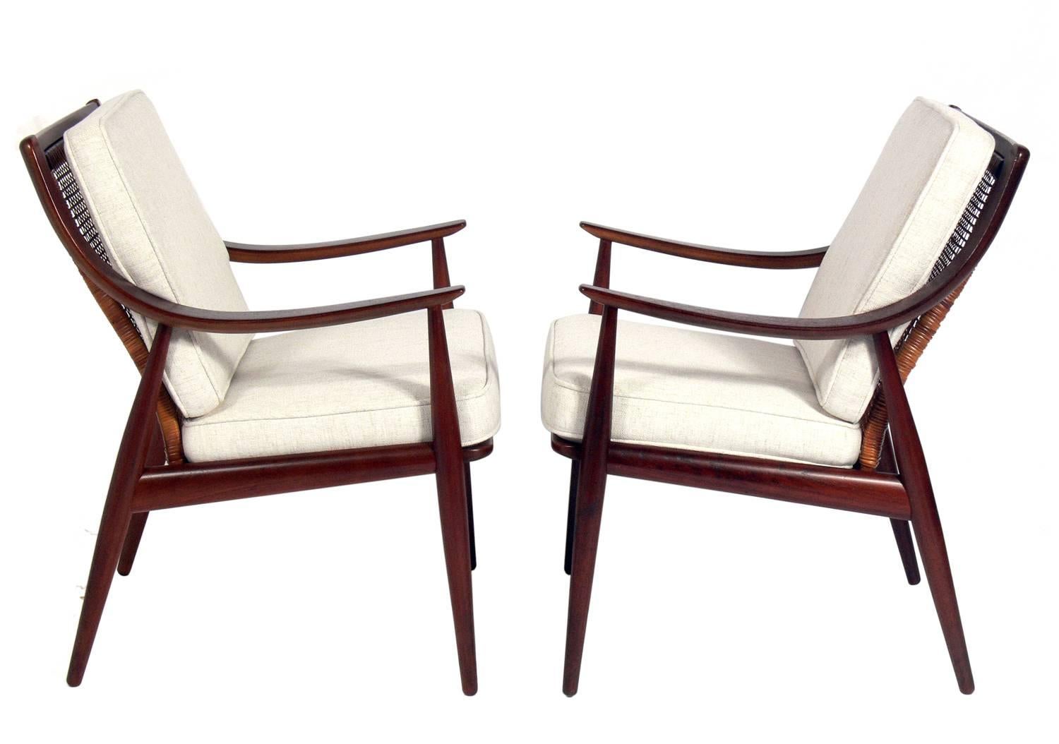 Pair of Danish modern lounge chairs, designed by Ib Kofod-Larsen for France & Daverkosen, Danish, circa 1950s. They came out of the same estate, and are a near pair, as the caning on the backs varies slightly. See last photos. They have been