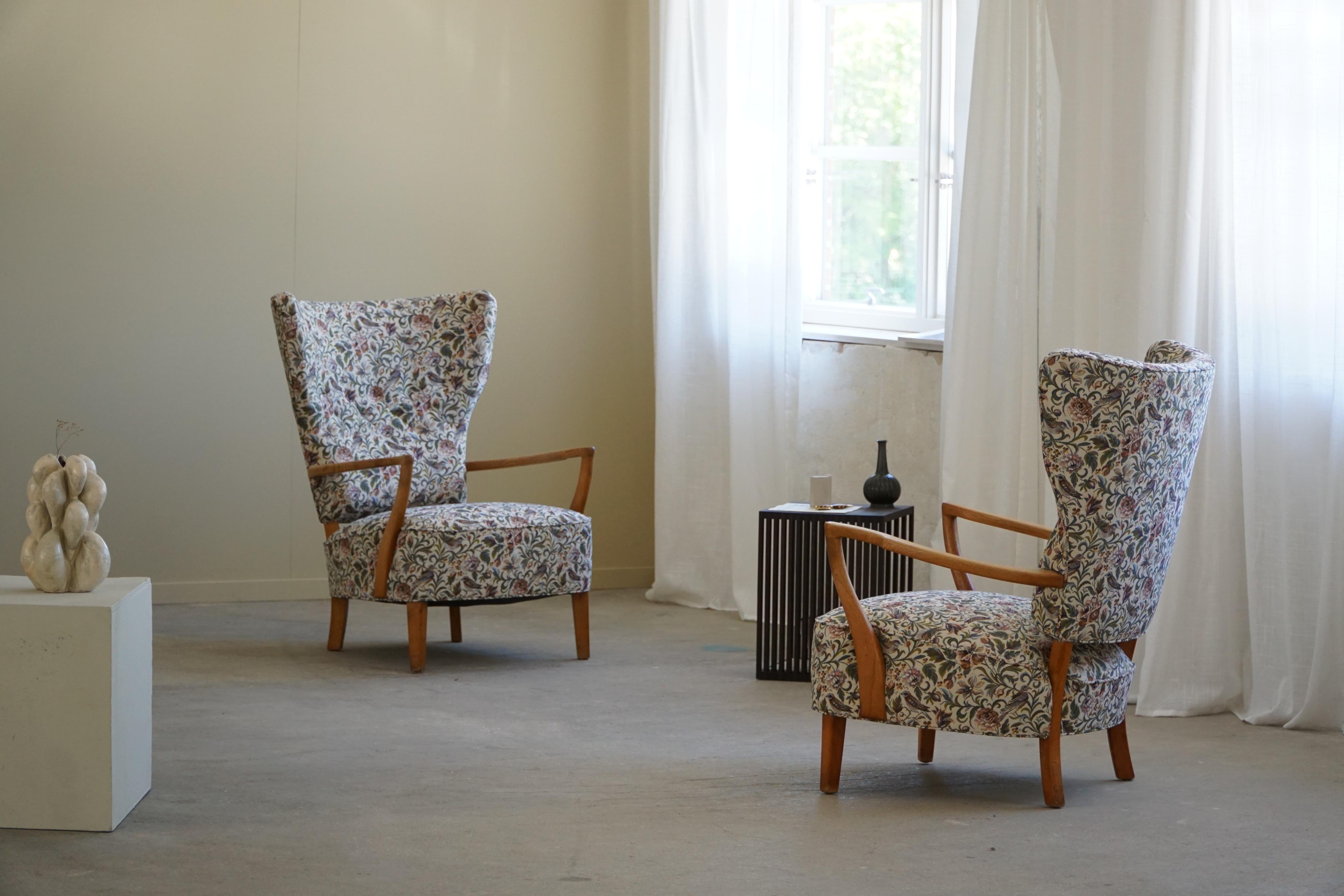 Presenting a stunning pair of lounge chairs from the 1950s, expertly crafted in oak and thoughtfully reupholstered with a touch of nostalgia using style fabric from the vibrant 1990s. Drawing inspiration from the iconic designs of Danish architect