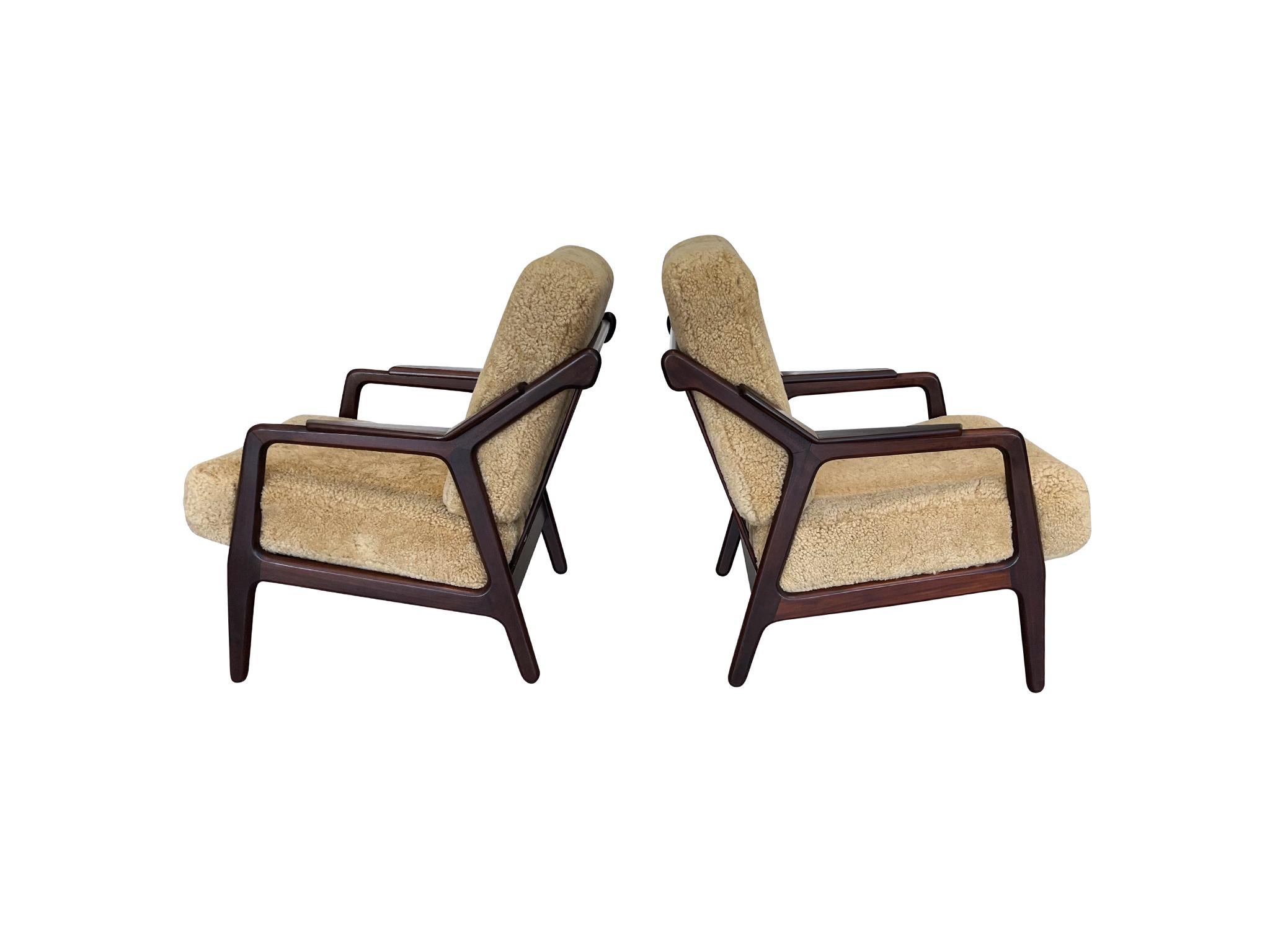 Everything about the design of these chairs exudes warmth. They are perfect for lounging. Crafted in the 1950s, they were designed by H. Brockmann-Petersen. They are walnut with new cushions and custom shearling upholstery. Angular forms and rounded