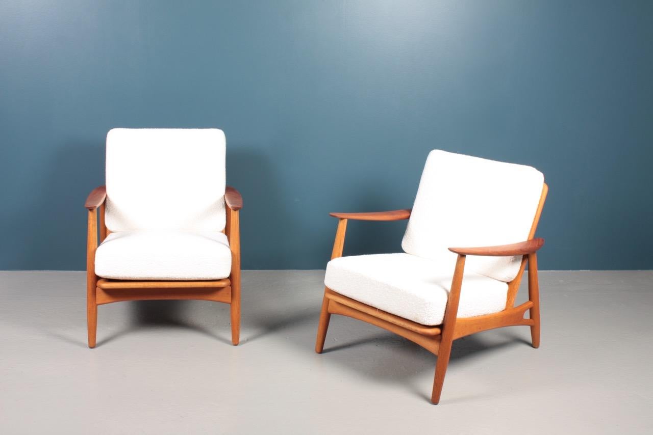 Pair of lounge chairs in teak, oak and upholstered with new bouclé. Designed by Johannes Andersen and made by Københavns Møbelfabrik A/S in 1960s. Great condition.