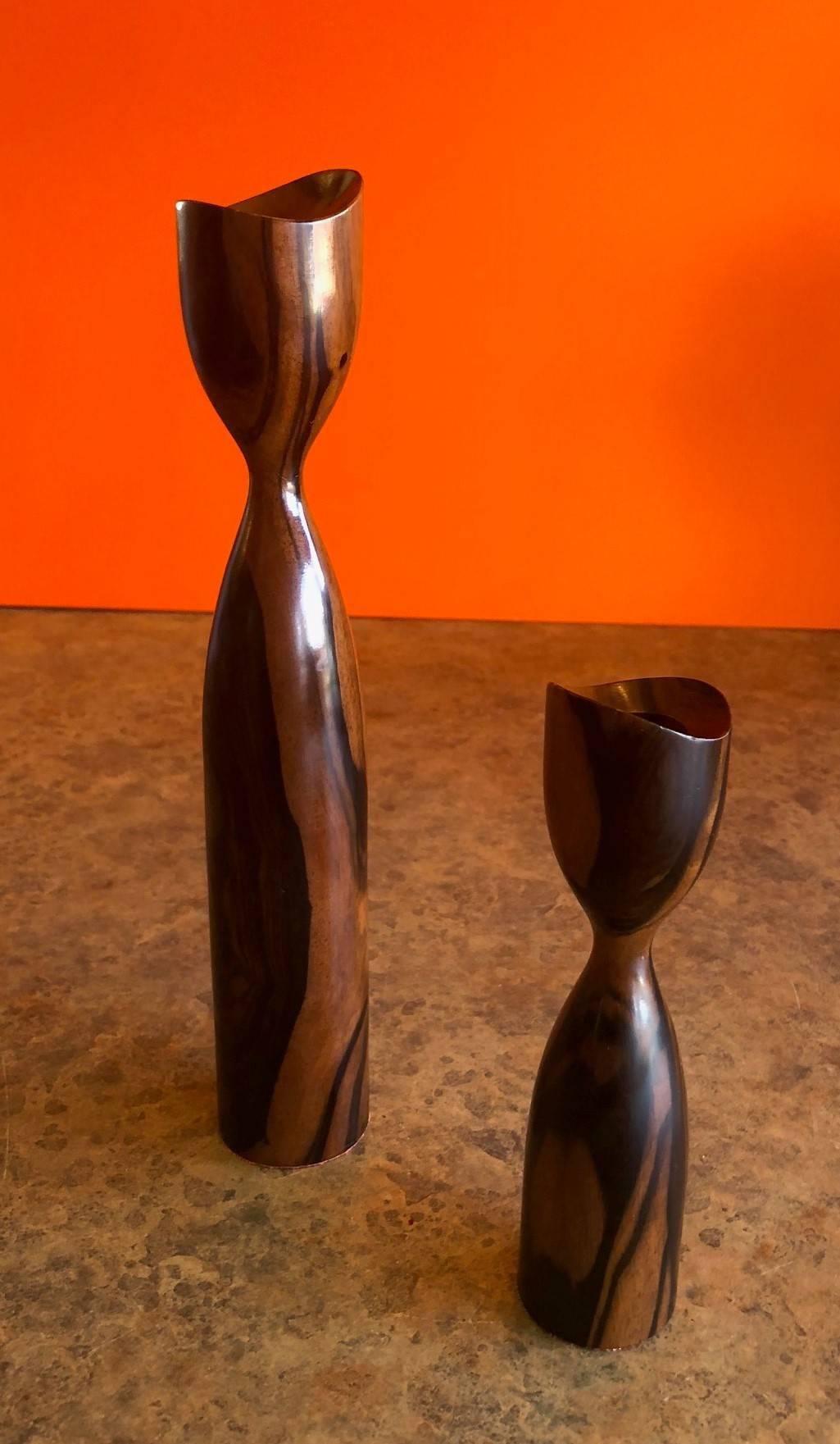 A gorgeous pair of highly polished Danish modern rosewood candlesticks, circa 1960's. The taller candlestick is 10