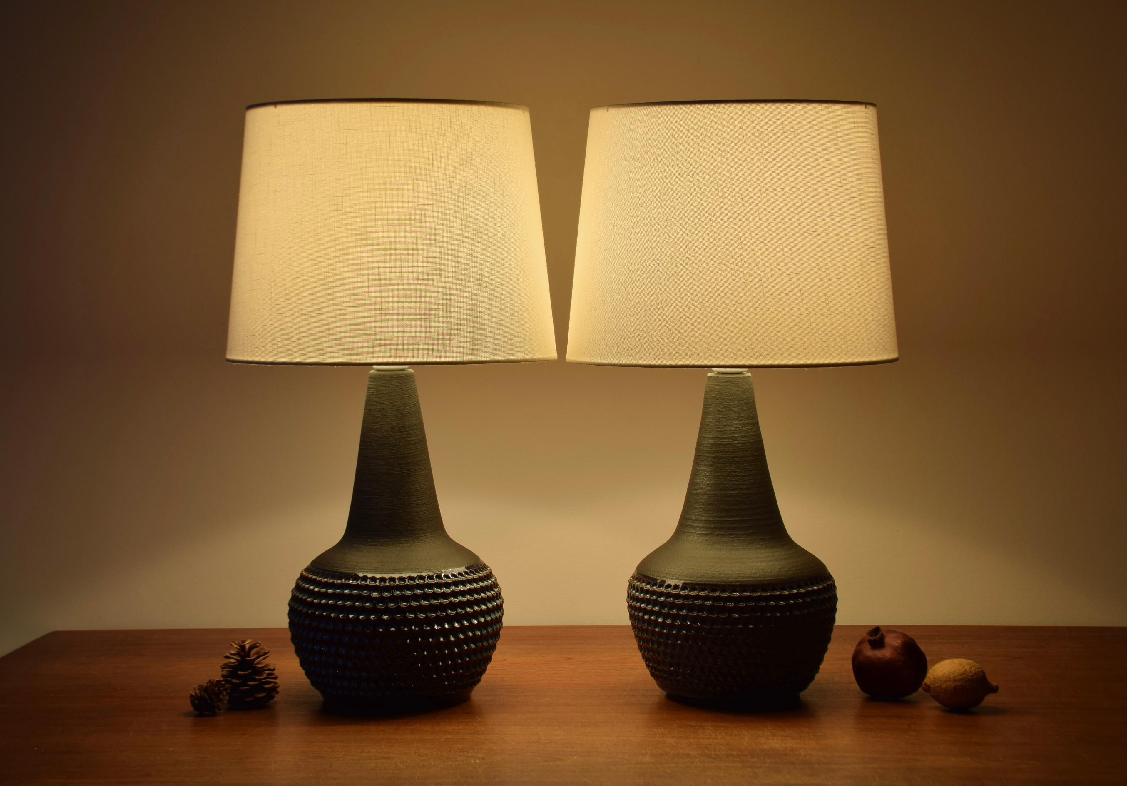 Pair of Midcentury Danish table lamps designed by Einar Johansen for Danish stoneware manufacturer Søholm. Manufactured circa 1960s.

The lamps have a matte dark brown glaze on neck and shoulder contrasted by a textured surface and glossy bluish