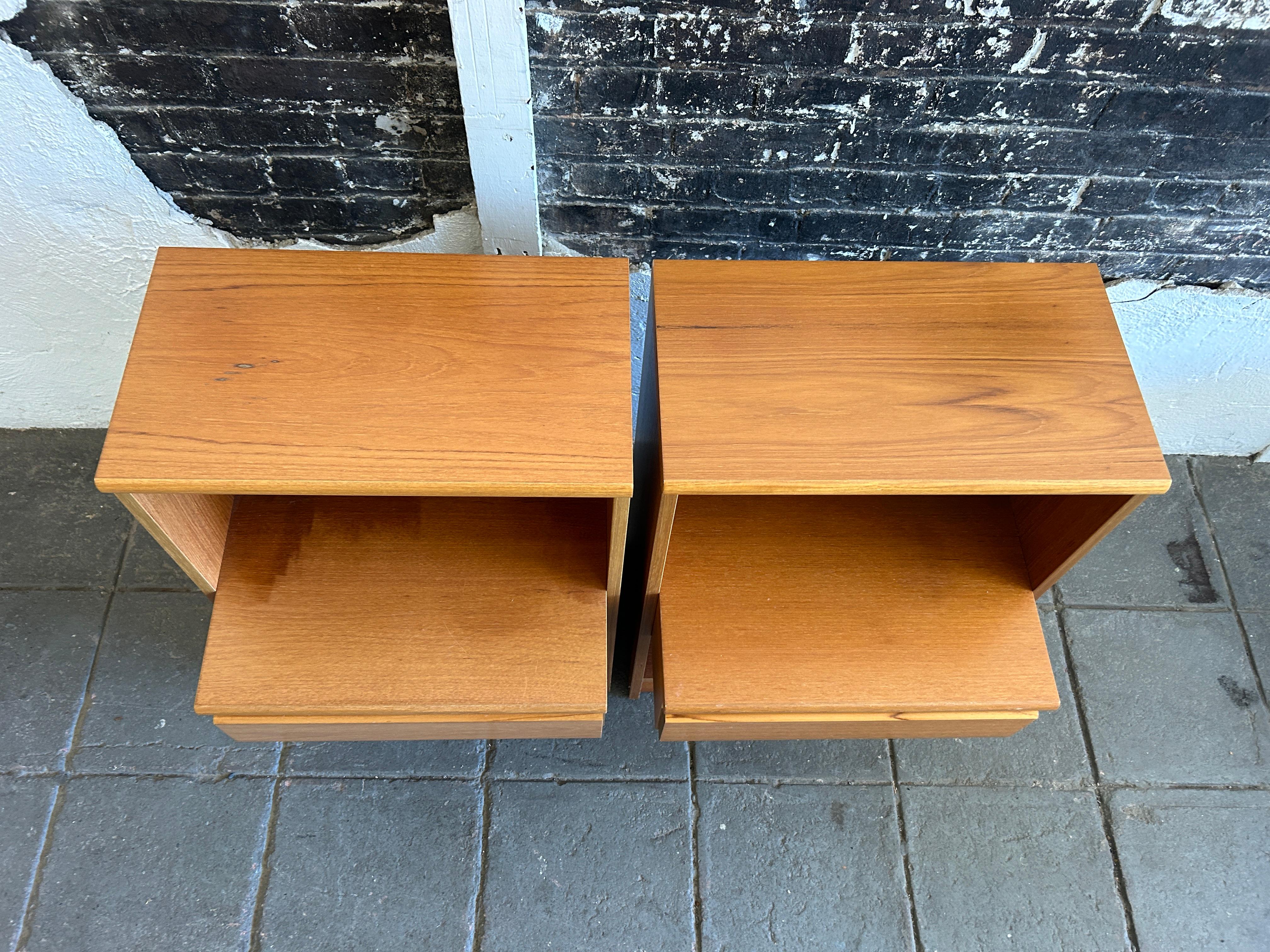Pair of danish modern single drawer teak nightstands. Light teak wood with upper and lower cubby and (1) center drawer on each nightstand. Simple Danish design circa 1970 made in Denmark. Located in Brooklyn NYC.

Sold as a set of (2) a pair of