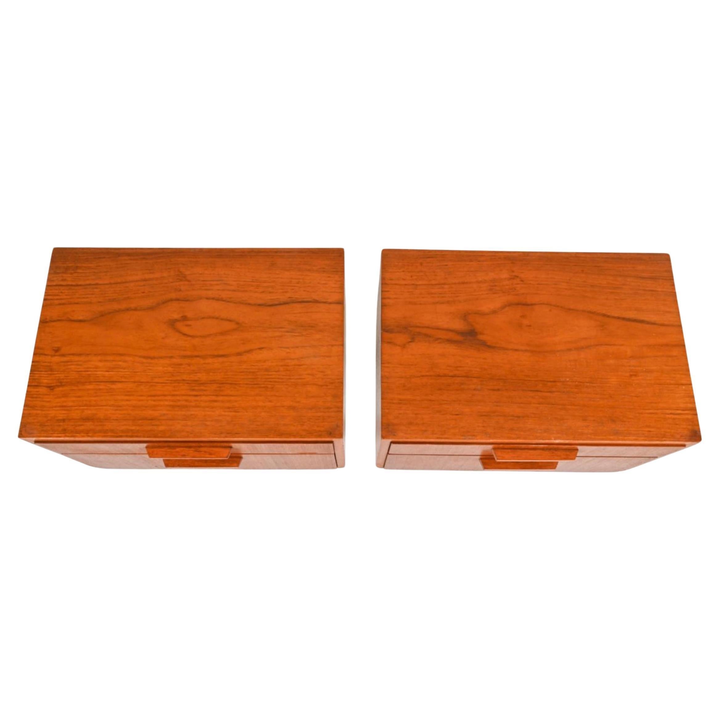 Coppia di comodini moderni danesi a un cassetto in teak con area di stoccaggio inferiore ribaltabile. Legno di teak marrone con (2) maniglie su ognuna delle gambe affusolate. Semplice design danese del 1970 circa, prodotto in Danimarca. Situato a