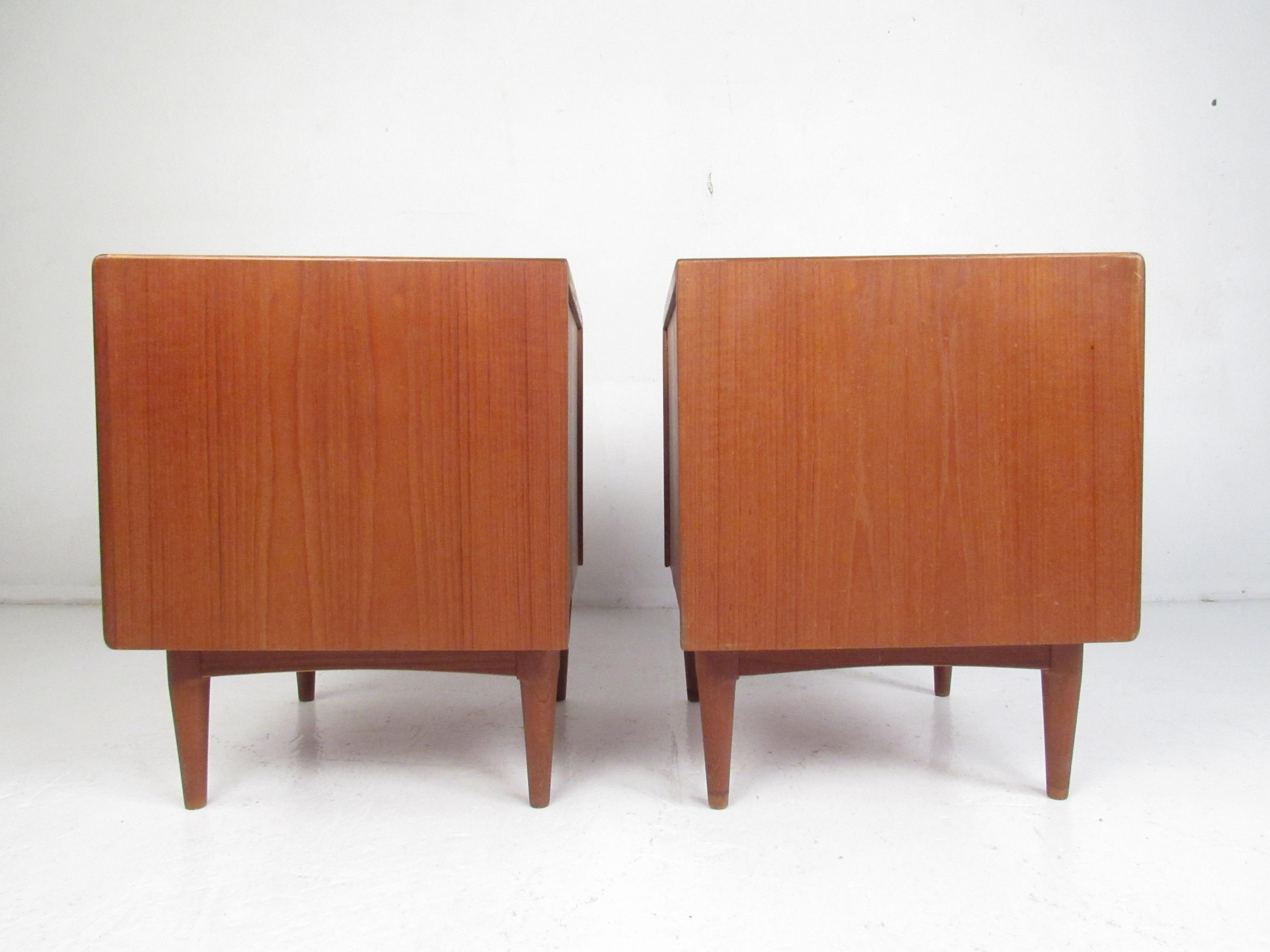 This stunning pair of Mid-Century Modern nightstands feature a large compartment with a drawer hidden by a tambour door. An unusual par of side tables with tambour doors that function vertically rather than horizontally. A sleek design with