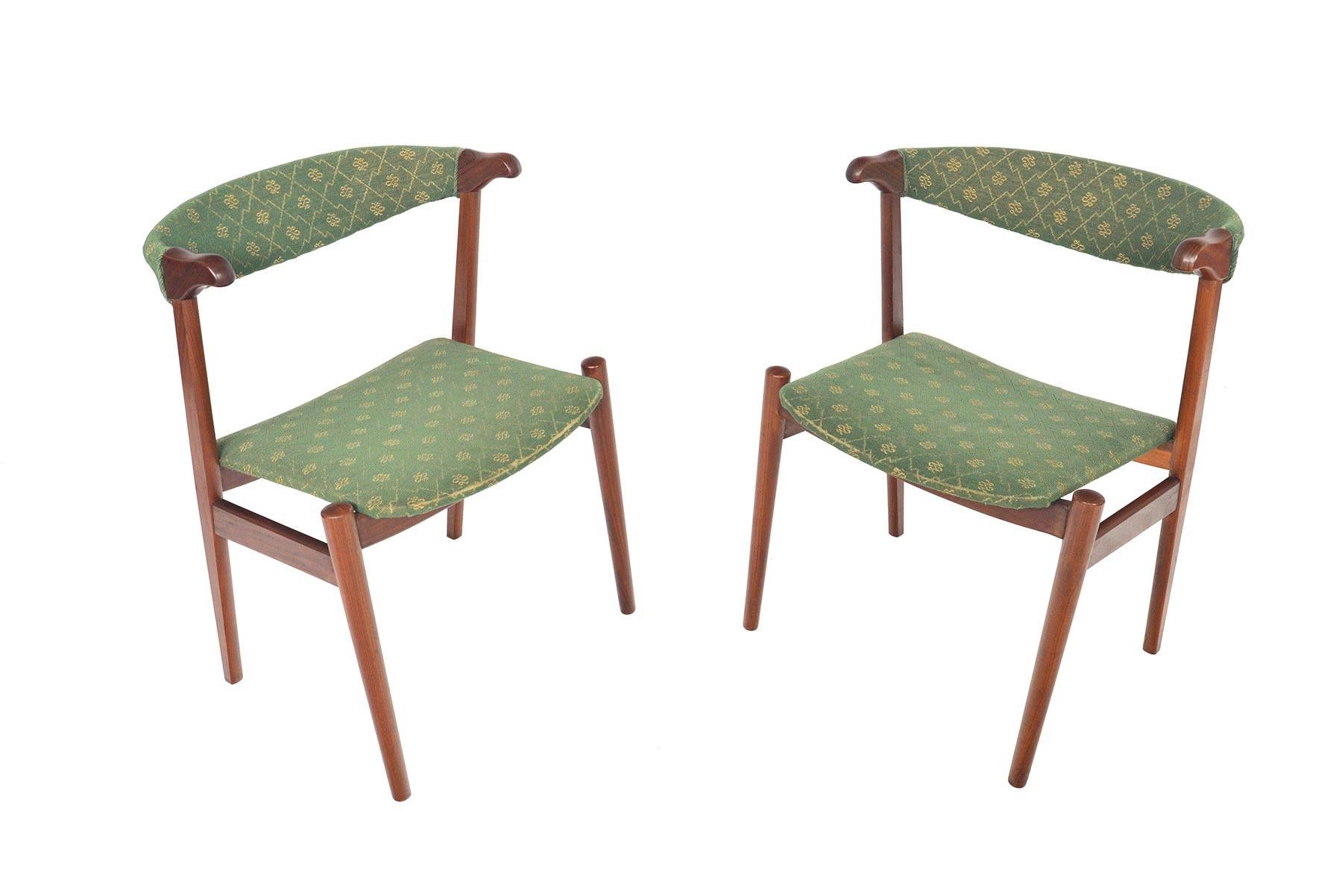 This Classic set of Danish modern armchairs offer a traditional silhouette crafted from teak afrormosia. Perfect for use as occasional chairs, paired with a dining set, or a desk, these chairs feature an upholstered backrest and small arms. Chairs