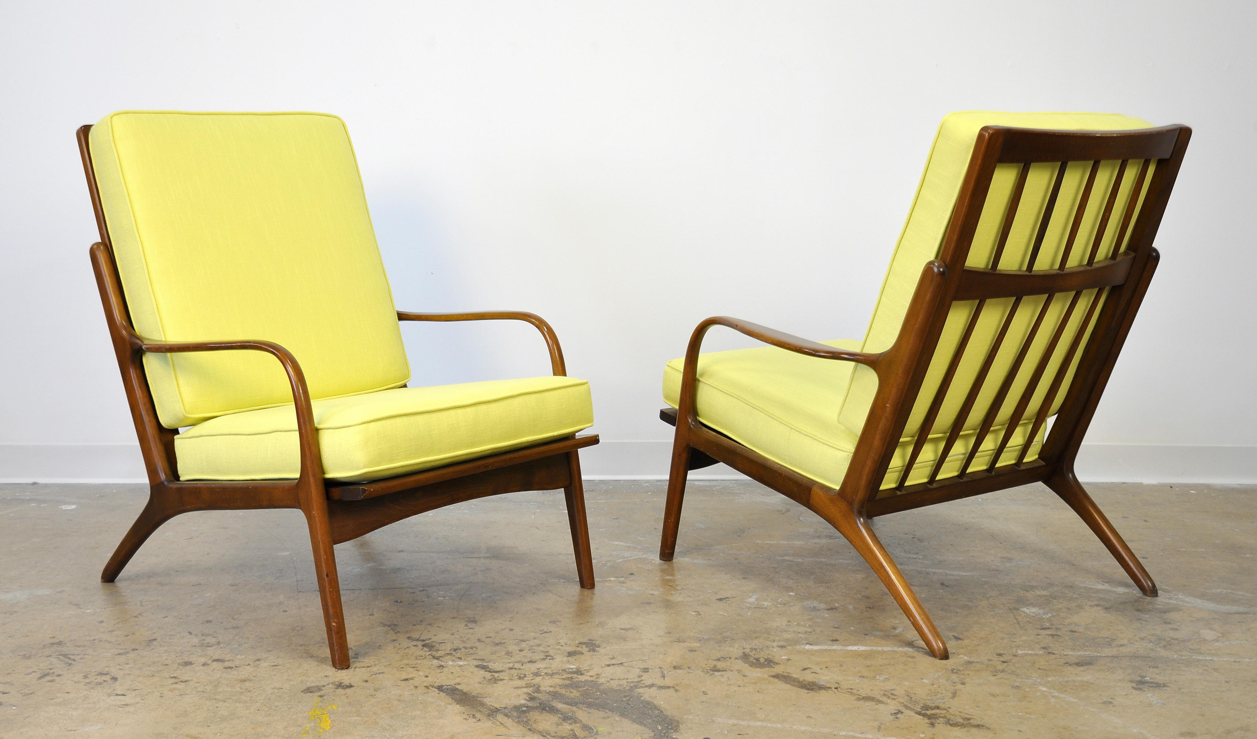 A pair of vintage midcentury high back armchairs, dating from the 1950s and attributed to designer Ib Kofod-Larsen. The frame of the easy chair has sleek, slender arms, a spindle high back and splayed legs. The lines are very similar to the bent arm