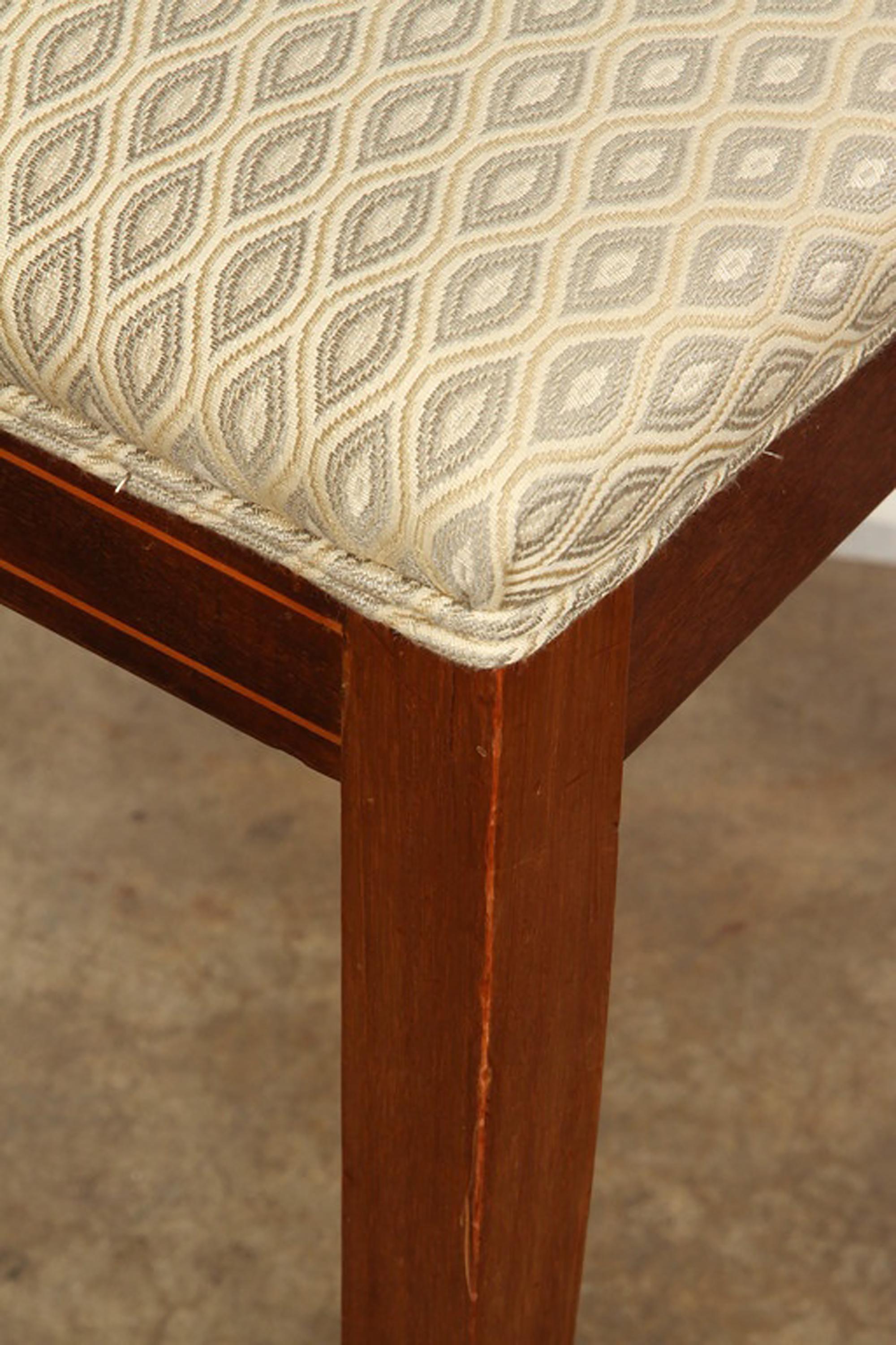 A pair of Danish marquetry and mahogany side chairs in the neoclassical style, circa 1820. Each with a slightly curved rectangular back marquetry-inlaid with an urn issuing scrolling foliage within a string-inlaid border, flanked by back-swept