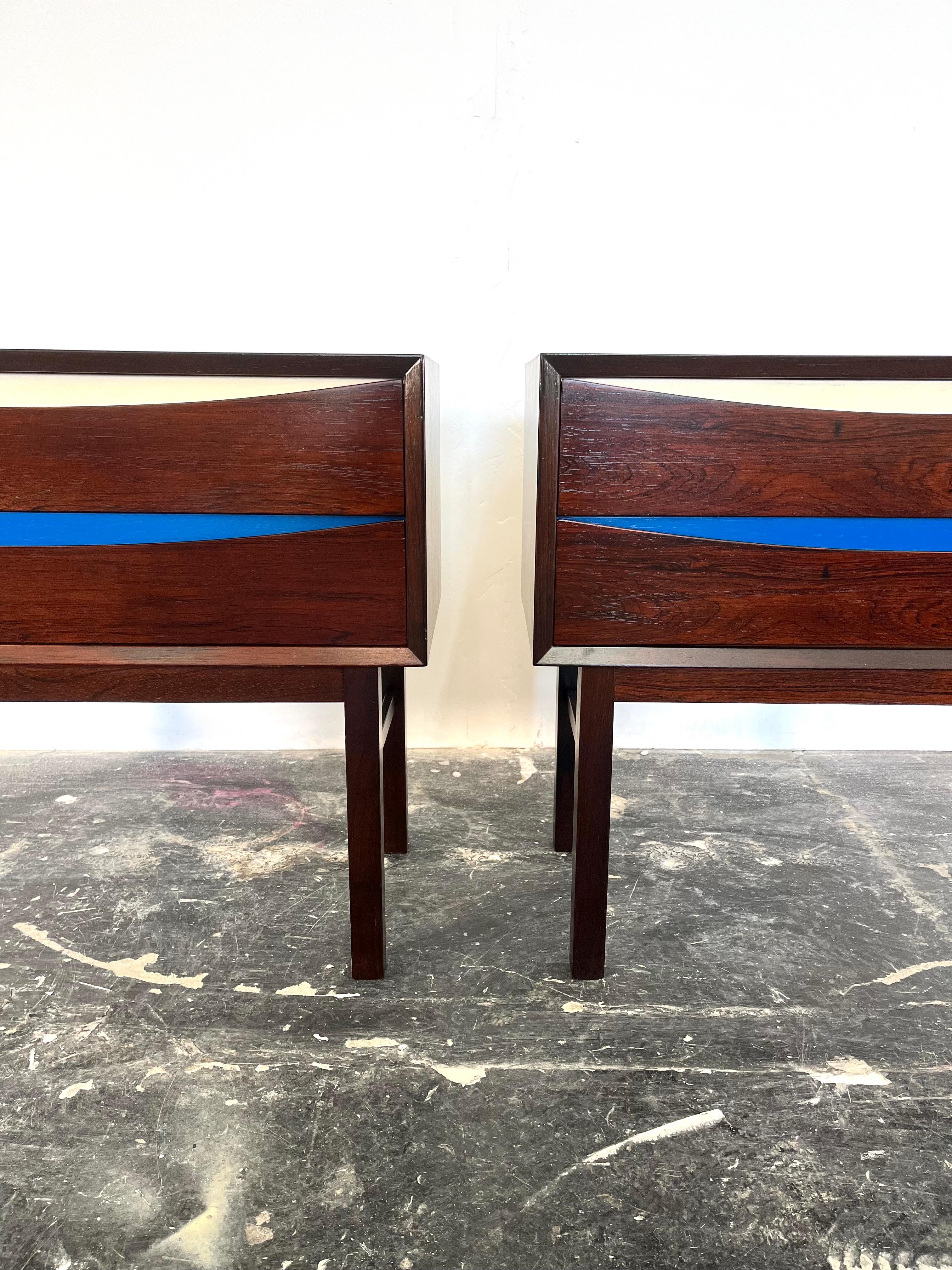 Pair of Danish Nightstands in Rosewood in the Style of Arne Vodder with Blue and white lacquered drawer fronts. These pieces feature stunning wood grain and great details such as long legs, eclipse drawer fronts, and beveled edges that have been