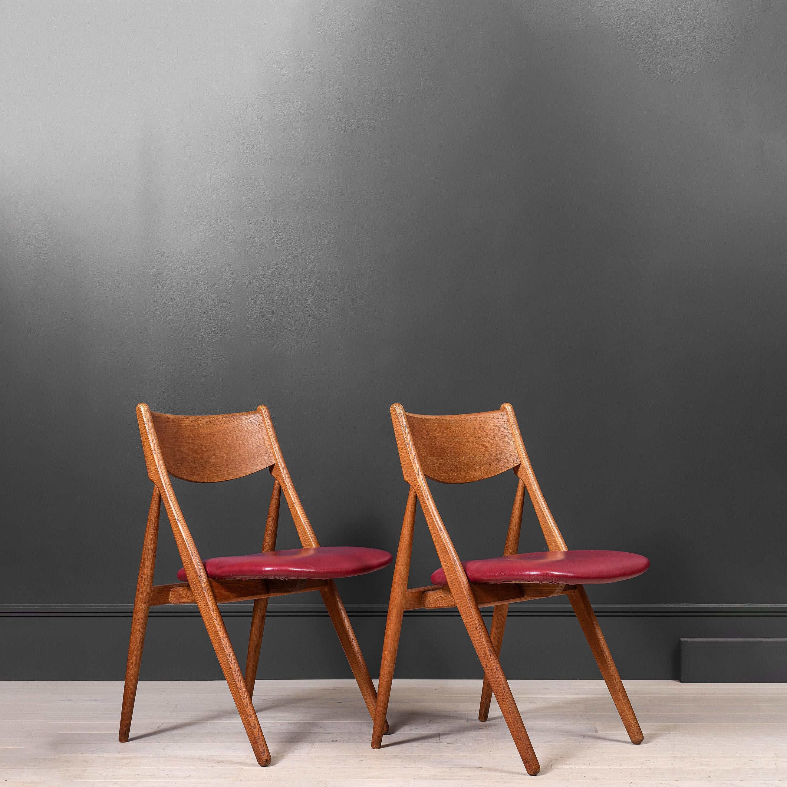 A matching pair of Danish midcentury chairs. Constructed from Oak with leather seat upholstery. Nice Minimal Modernist Scandinavian design. Reupholstery available upon request