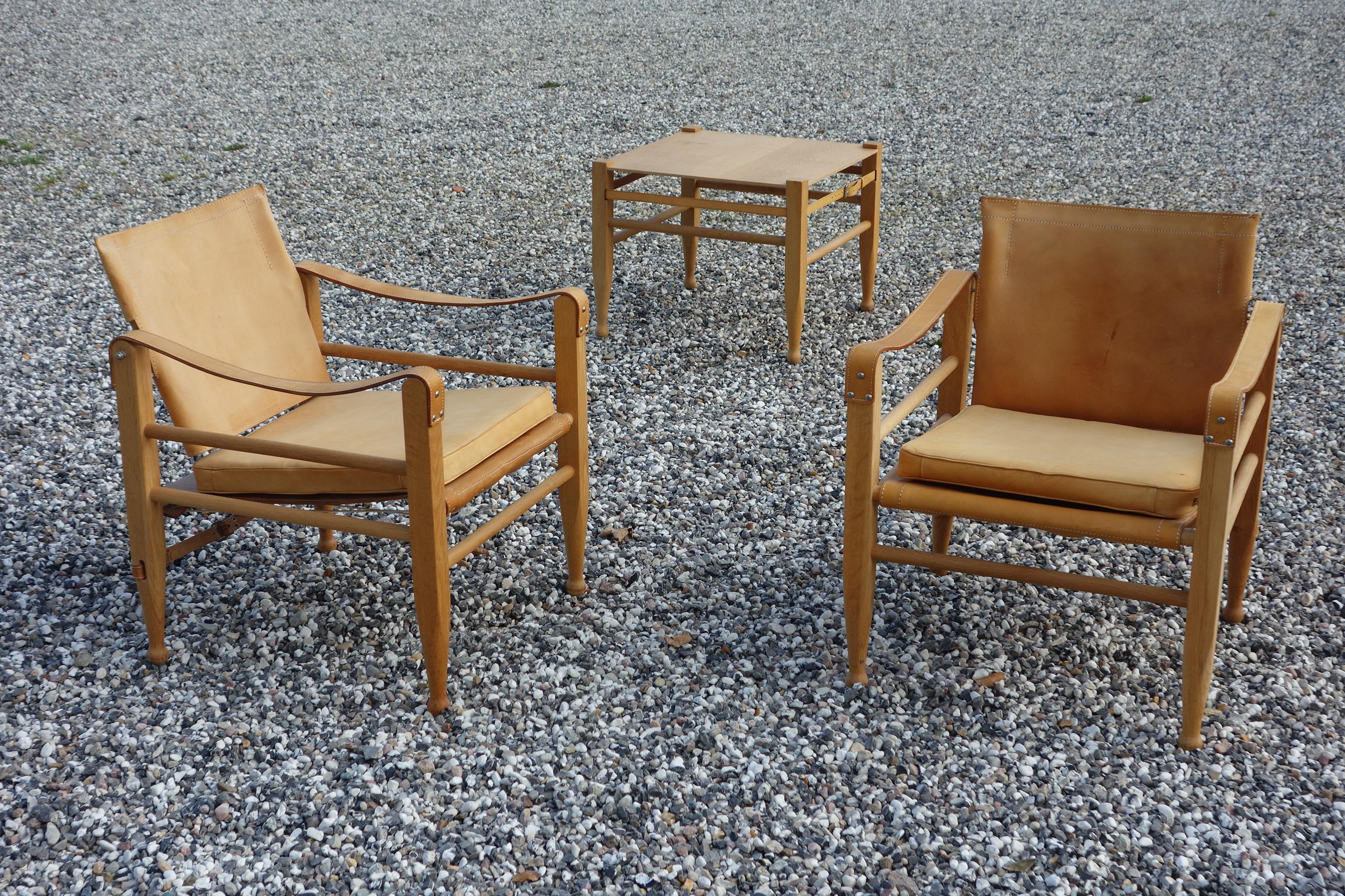 A pair of Danish oxhide safari chairs Kaare Klint style from 1970. Attributed to Børge Mogensen and lately to Aage Bruun & Son. Extremely well kept and mint condition. Comes with the original table that is rarely seen. A beautiful set of safari