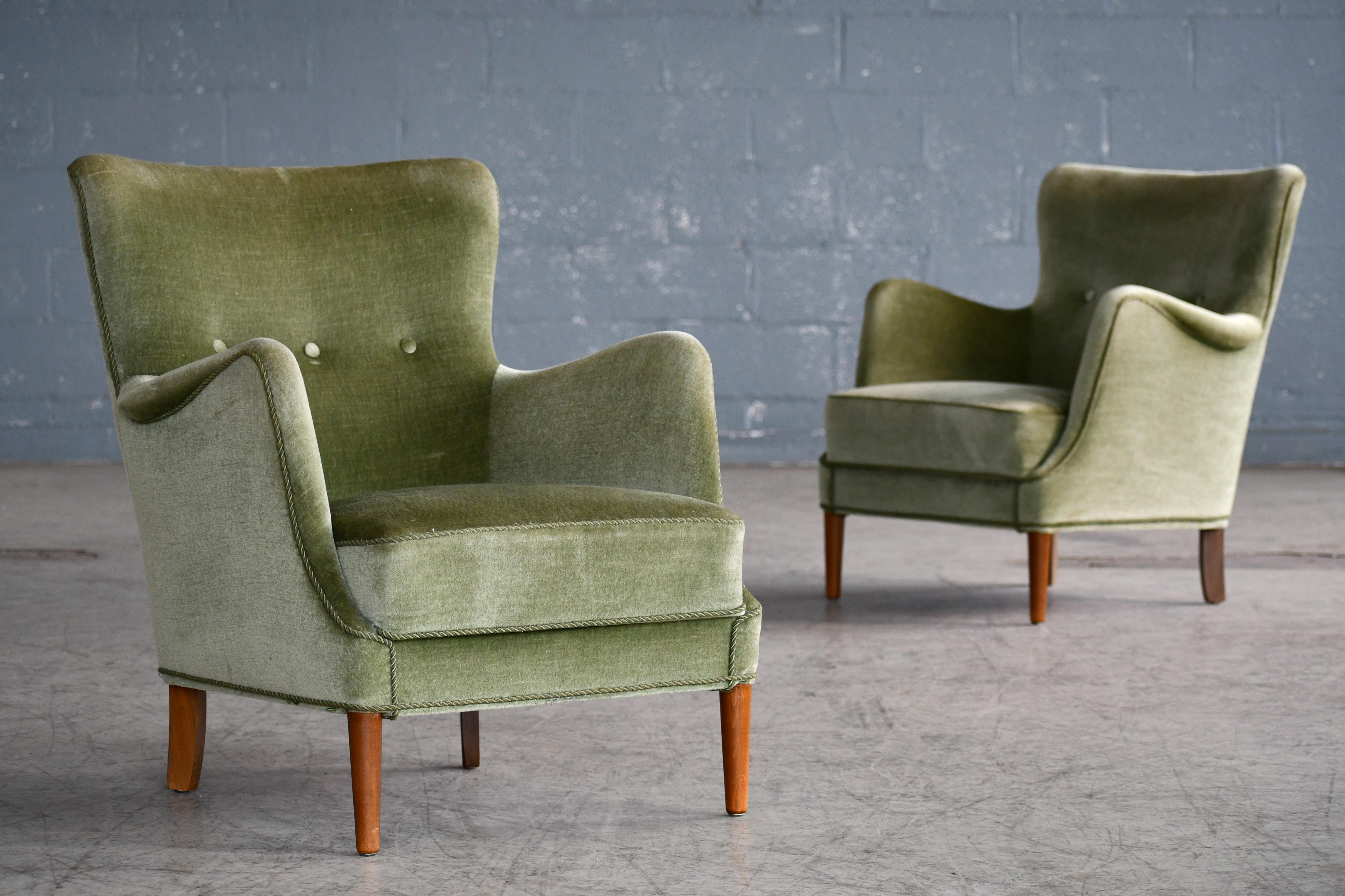 Elegant pair of 1950s small scale lounge chairs attributed to Peter Hvidt and Orla Molgaard made in Denmark between 1940-1950. The chairs exhibit the rolled armrest detail and tapered front legs often preferred by Peter Hvidt. Comfortable and sturdy