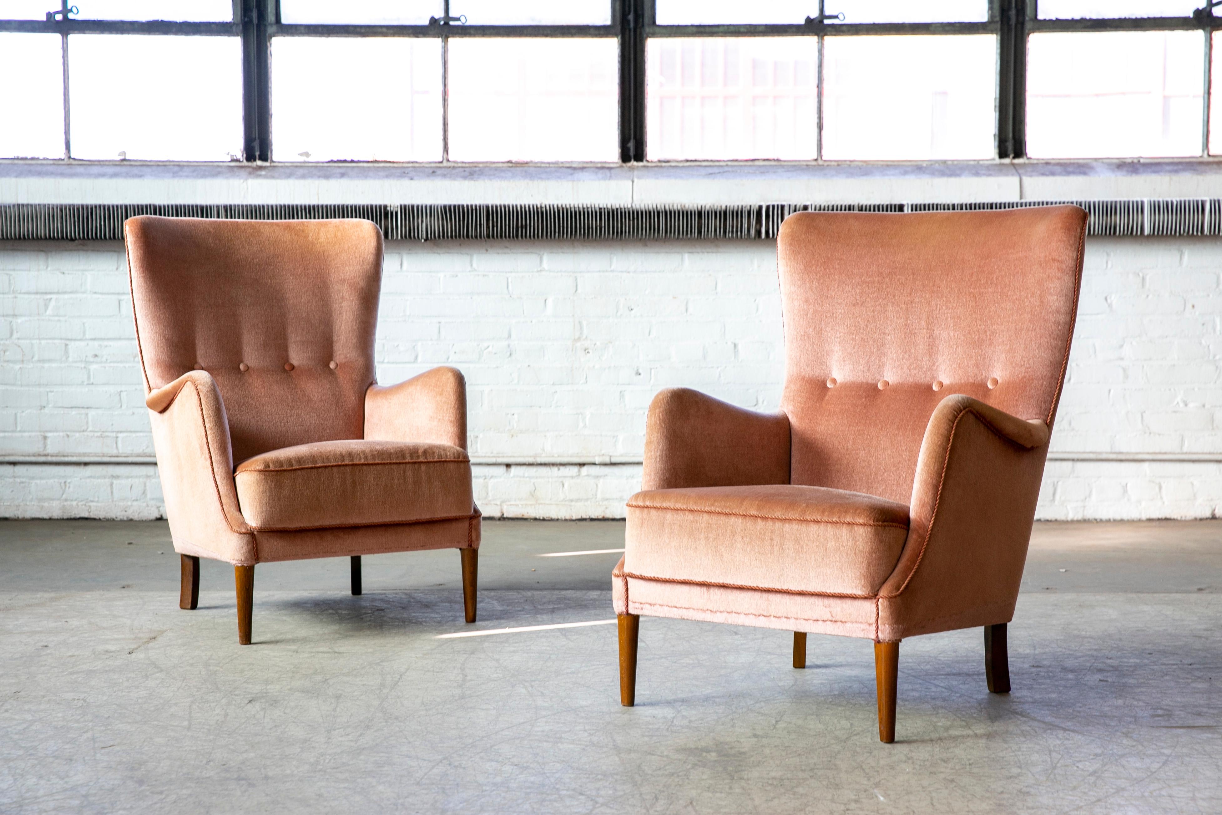 Elegant pair of 1950s lounge chairs attributed to Peter Hvidt and Orla Molgaard made in Denmark between 1940-1950 and most likely manufactured by Fritz Hansen. The chairs exhibit the rolled armrest detail and tapered front legs often preferred by