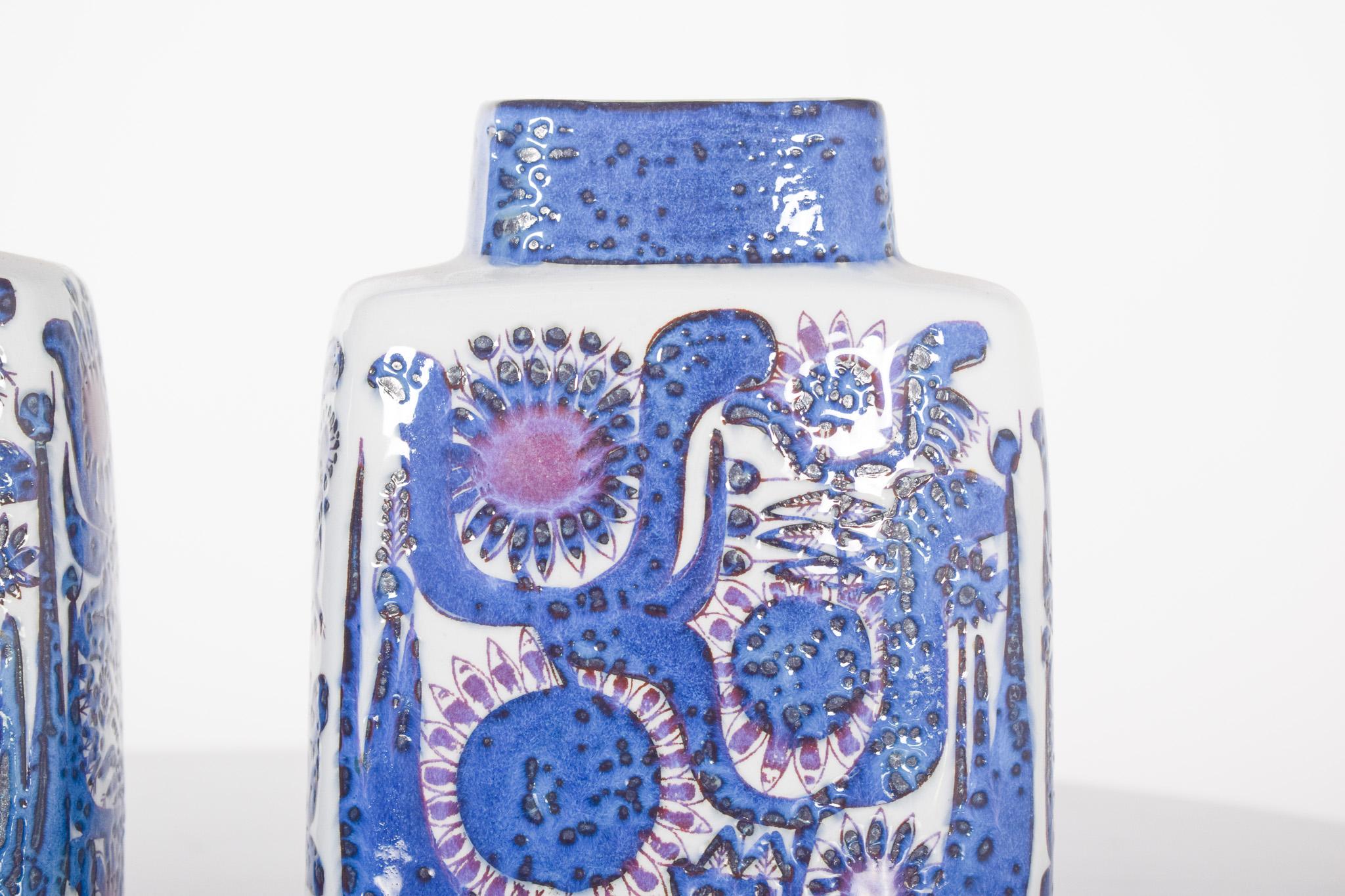 Coppia di vasi in ceramica danese, Royal Copenhagen Tenera. Di forma rettangolare con angoli arrotondati, con uno sfondo bianco brillante e corpi decorati con rilievi dipinti in vivaci tonalità di blu, viola e nero.
Il motivo rappresenta fiori e