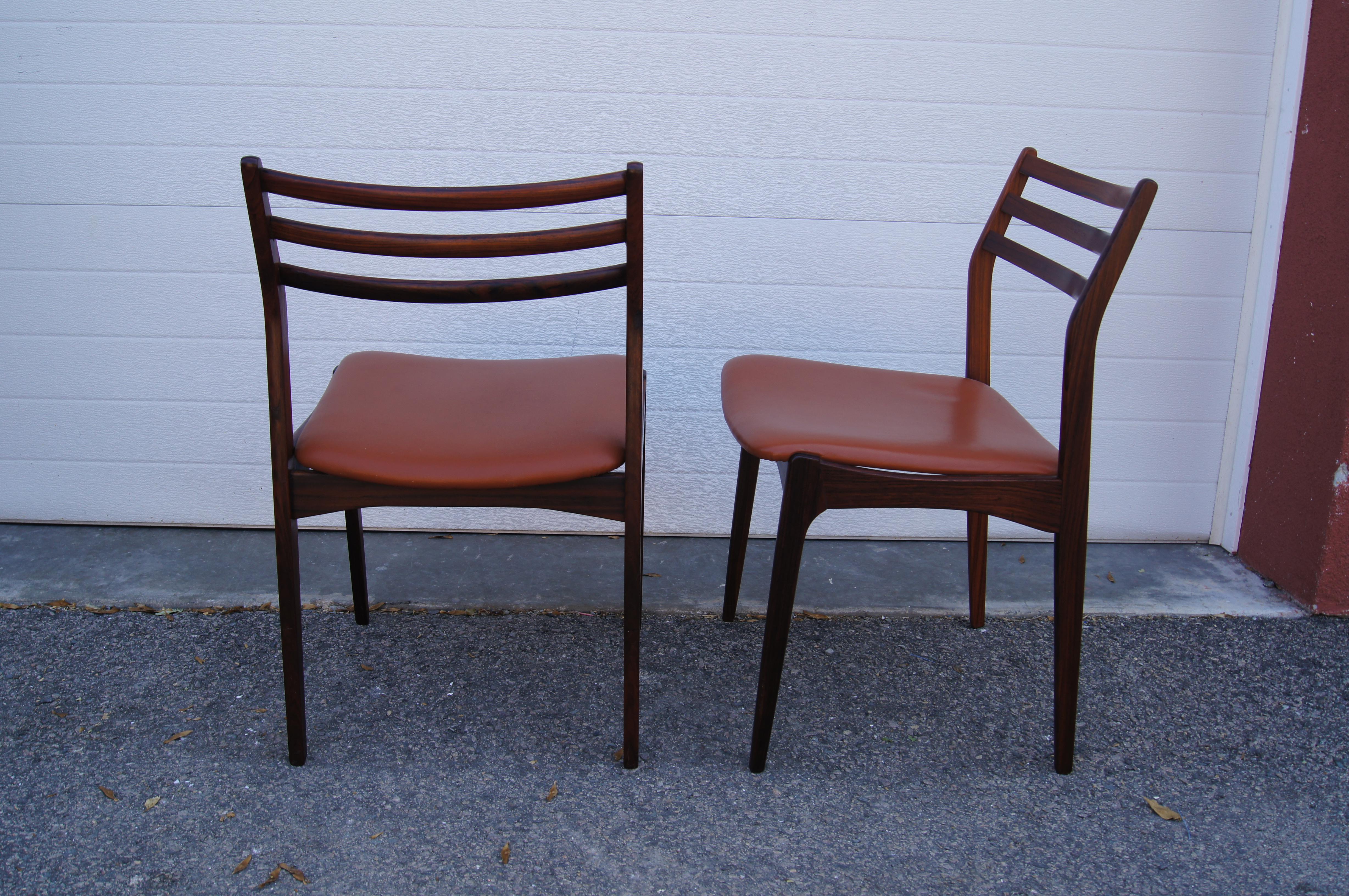 This elegant pair of Danish modern side chairs features frames of solid rosewood with canted back rests and leather-upholstered seats.