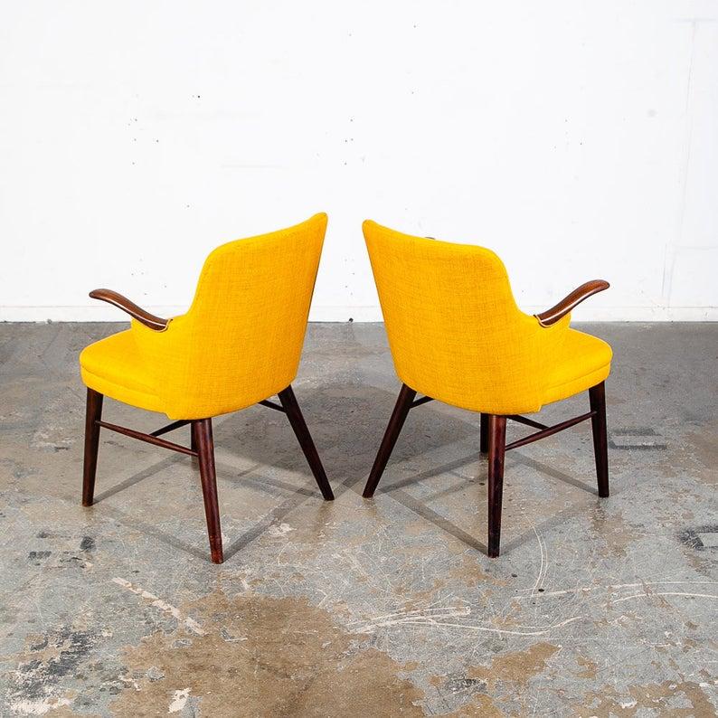 Pair of Scandinavian armchairs / lounge chairs in dark solid Brazilian rosewood and reupholstered in yellow fabric. The solid rosewood wood arms offer a unique sculpted design that adds are certain sophistication to these chairs. This set was
