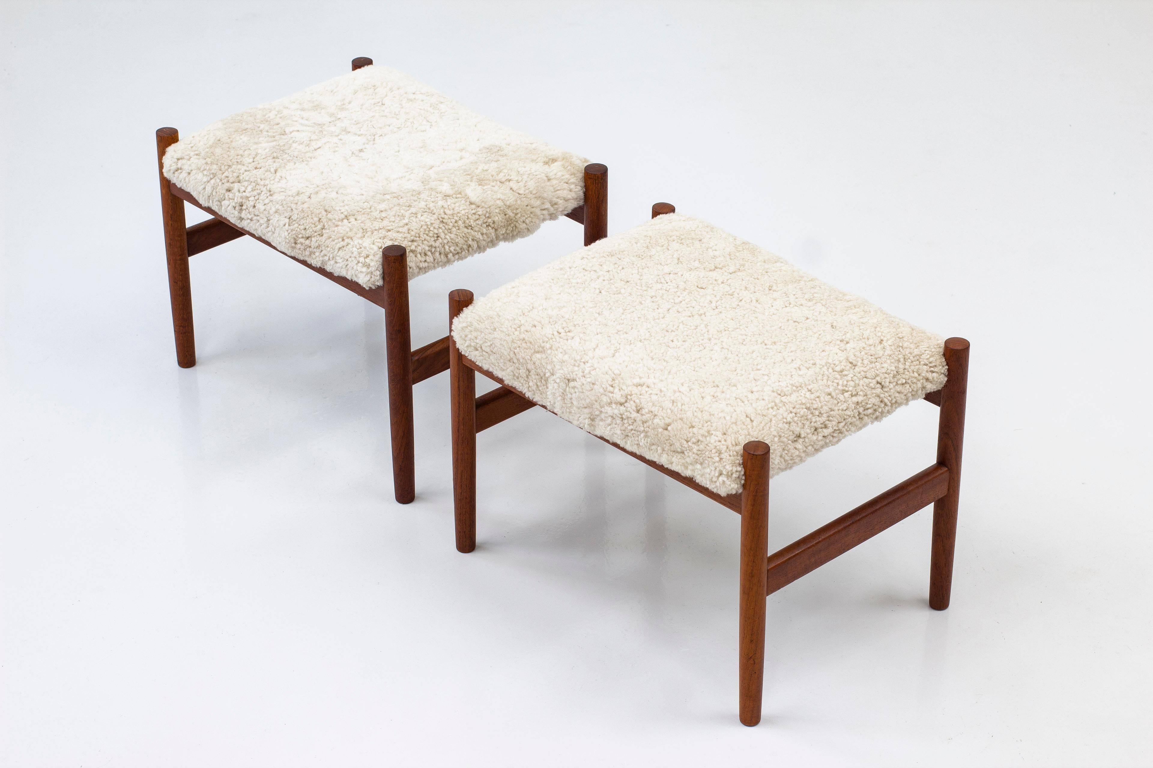 Pair of stools designed by Hugo Frandsen. Produced by his own company in Denmark during the 1960s. Made from solid teak with new sheep skin upholstery. Very good vintage condition with light signs of age related wear and patina. Upholstery is new