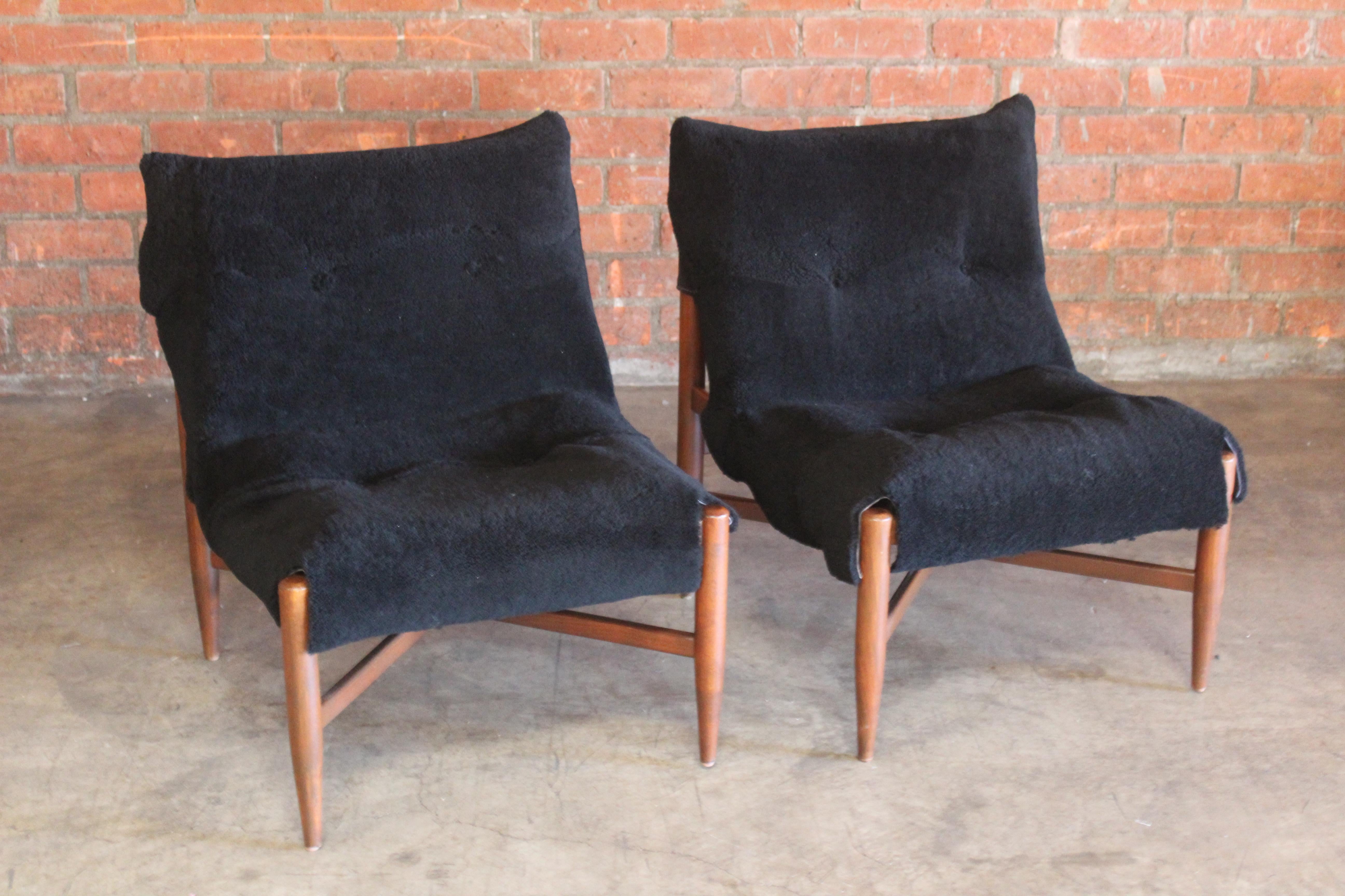 Pair of Danish 1960s slipper chairs with new suede slings and black sheepskin upholstered cushions. The sheepskin drape over new linen cushions. The beech wood frames have been refinished. The pair are in excellent condition.