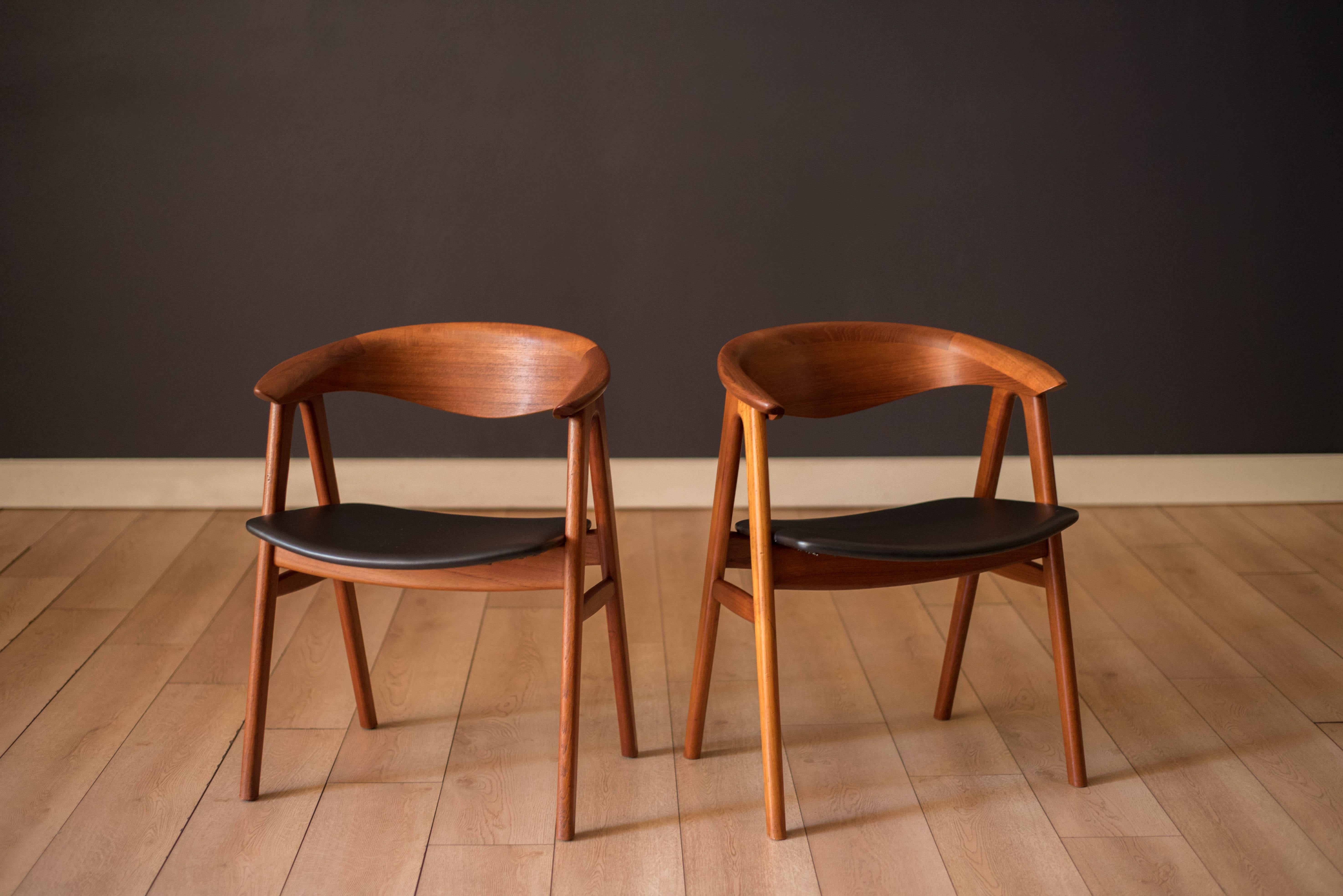 Pair of Mid Century Modern Compass dining chairs in teak designed by Erik Kirkegaard for Hong Stølefabrik, Denmark model no. 52 imported by Dux. This  side chair set features sculpted backrests and the seats have been newly reupholstered in black