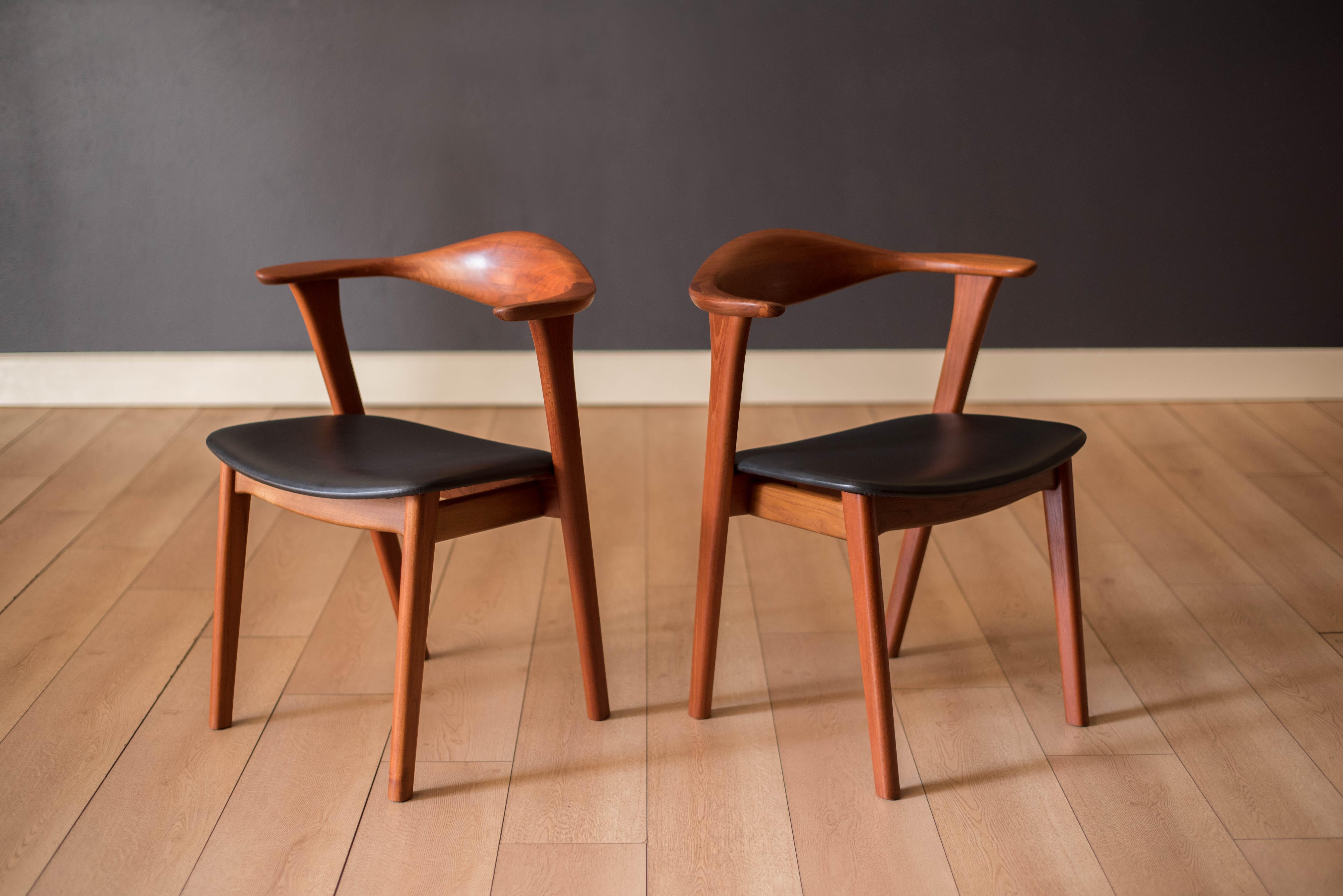 Pair of Mid-Century Modern armchairs in teak designed by Erik Kirkegaard for Høng Stolefabrik, Denmark. This set features a curved backrest with detailed joinery and sculpted arms. Retains the original black vinyl seat cushion. Perfect to use as a