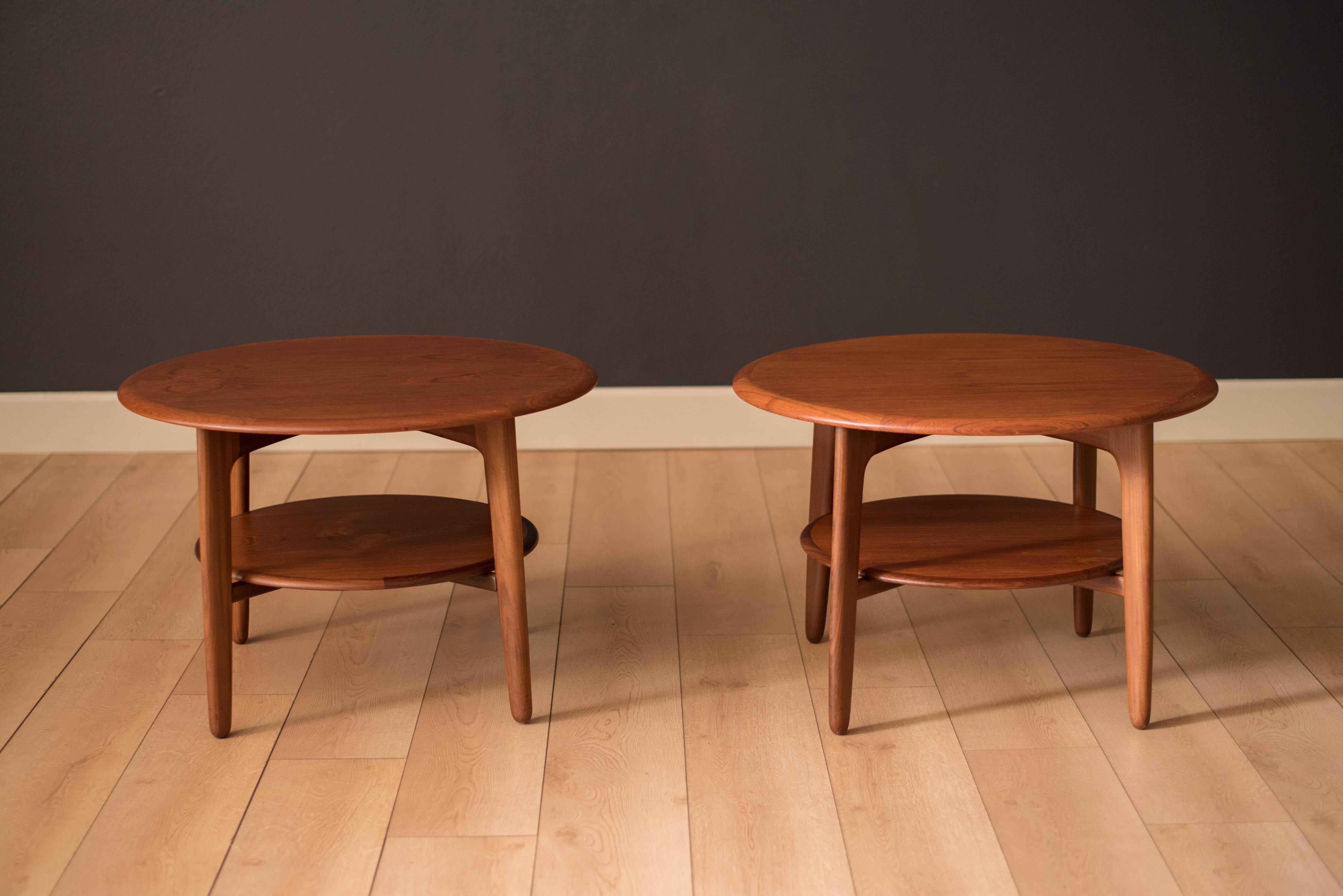 Mid century pair of matching side tables designed by Svend Madsen in teak. This set features a round top with solid edge banding and a lower tier for more display space.