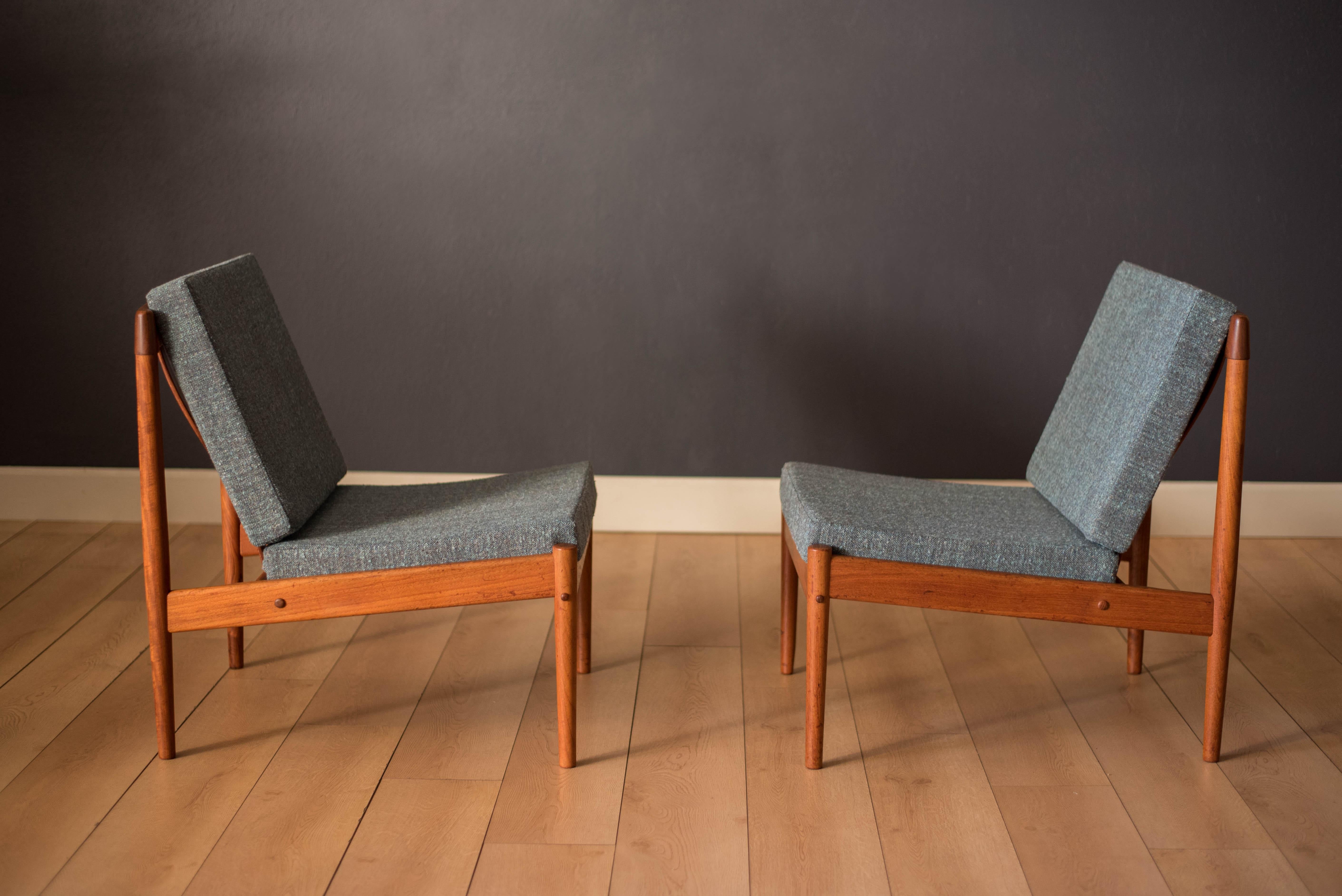 Mid Century slipper lounge chairs designed by Grete Jalk for Poul Jeppesen Mobelfabrik, made in Denmark. Features an armless modern design with a sculpted teak frame. This set has been reupholstered in a soft blue tweed blend and brand new straps.