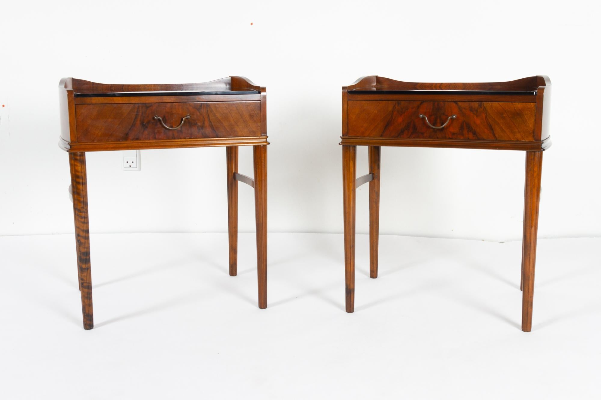 Pair of Danish walnut bedside tables, 1950s.
Two identical nightstands in walnut veneer with round tapered oak legs. Top in black glass with etching. Drawer with brass pull.
Very light and elegant.
Good vintage condition.