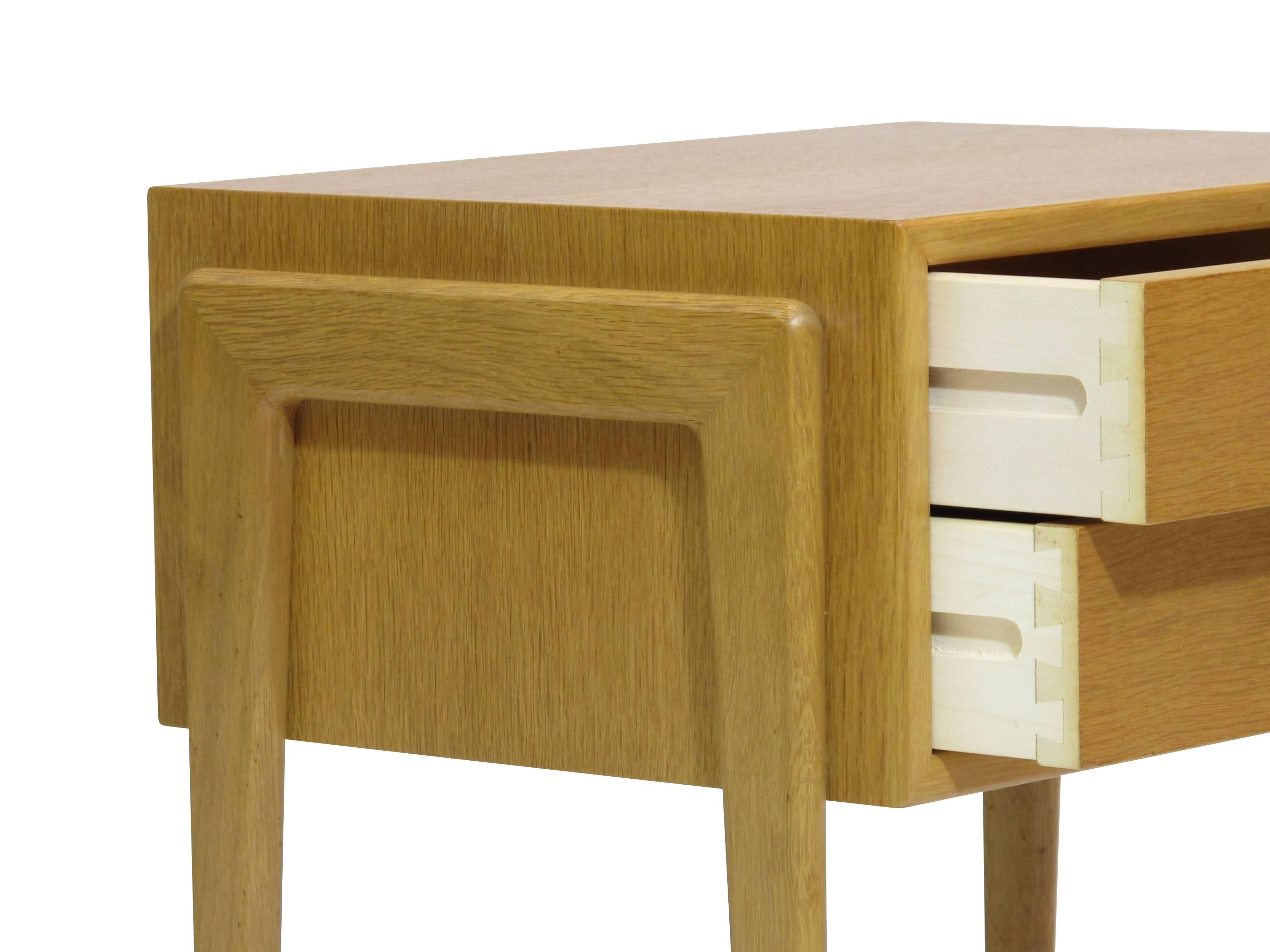 Midcentury nightstands crafted of white oak veneer over solid wood core, each with two drawers raised on solid oak legs. Original finish in excellent condition.