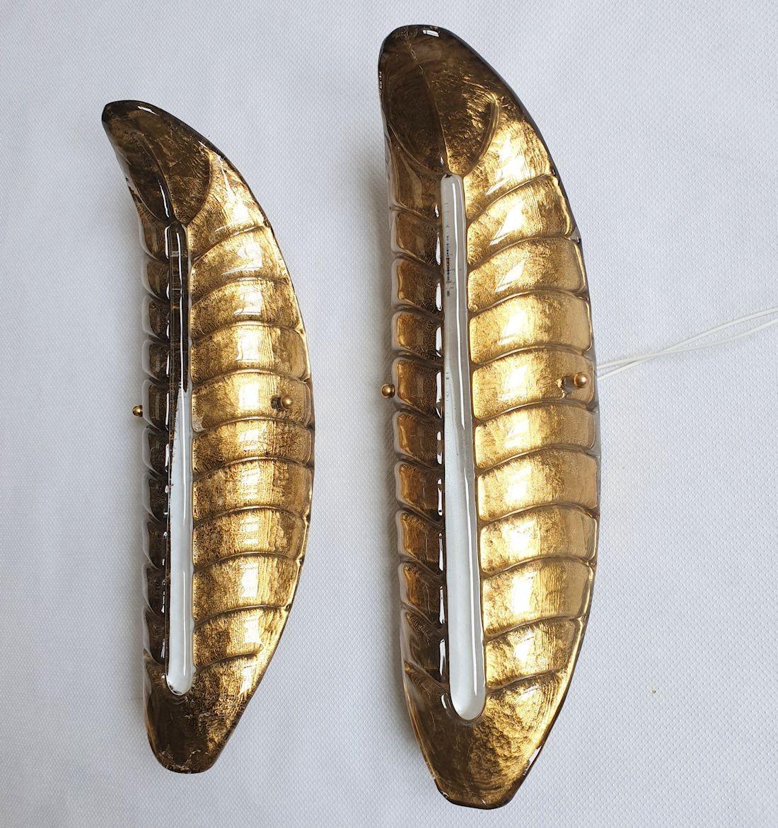 Pair of dark gold leaf Murano glass wall sconces, attributed to Barovier & Toso, Italy 1980s.
The mid century modern sconces are made of a single stylized leaf shaped Handmade Murano glass piece.
The glass is in a translucent dark gold color, with