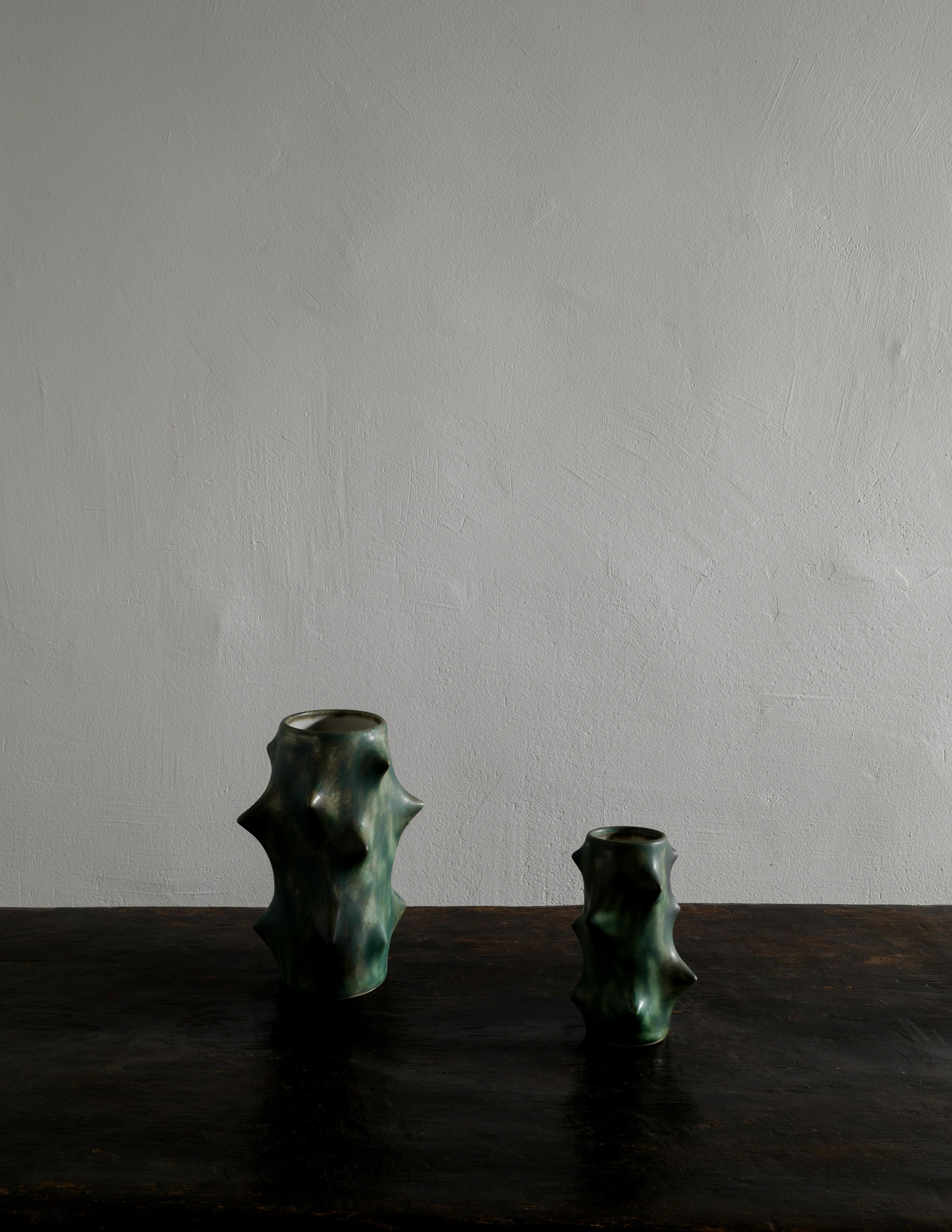 Rare paire de vases épineux en glaçure vert foncé, conçus par Knud Basse et produits par Michael Andersen, Danemark. Les deux vases sont en bon état vintage avec de petits signes d'utilisation et signés / marqués au bas. 
Nous disposons également