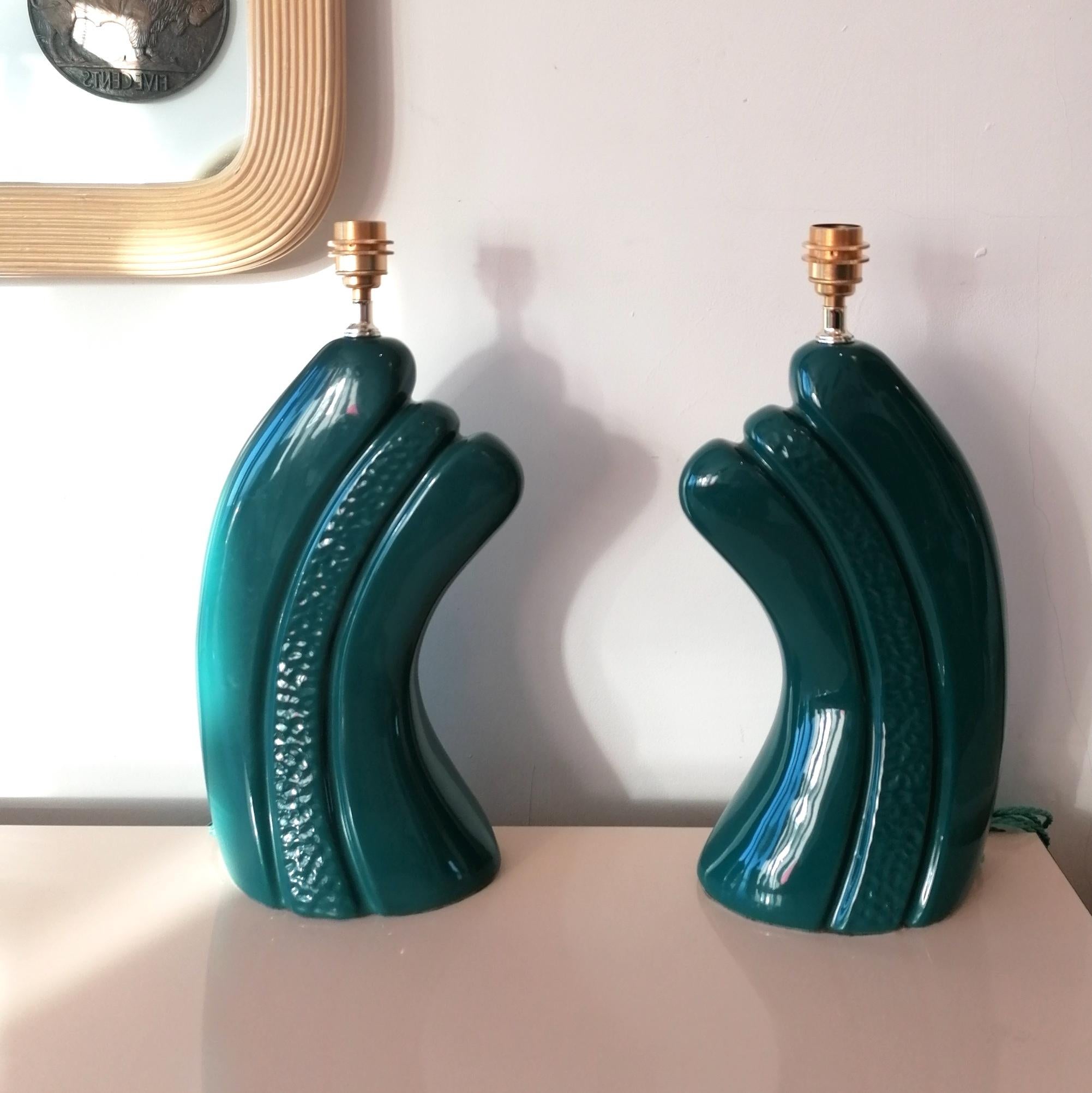 A pair of curvaceous dark, intense bluey green ceramic lamps, USA 1980s Art Deco revival. Newly rewired with braided cord.

Dimensions : height to top of bulb holder 49cm, width of body 23cm, depth 15cm, diameter of shade 41cm.