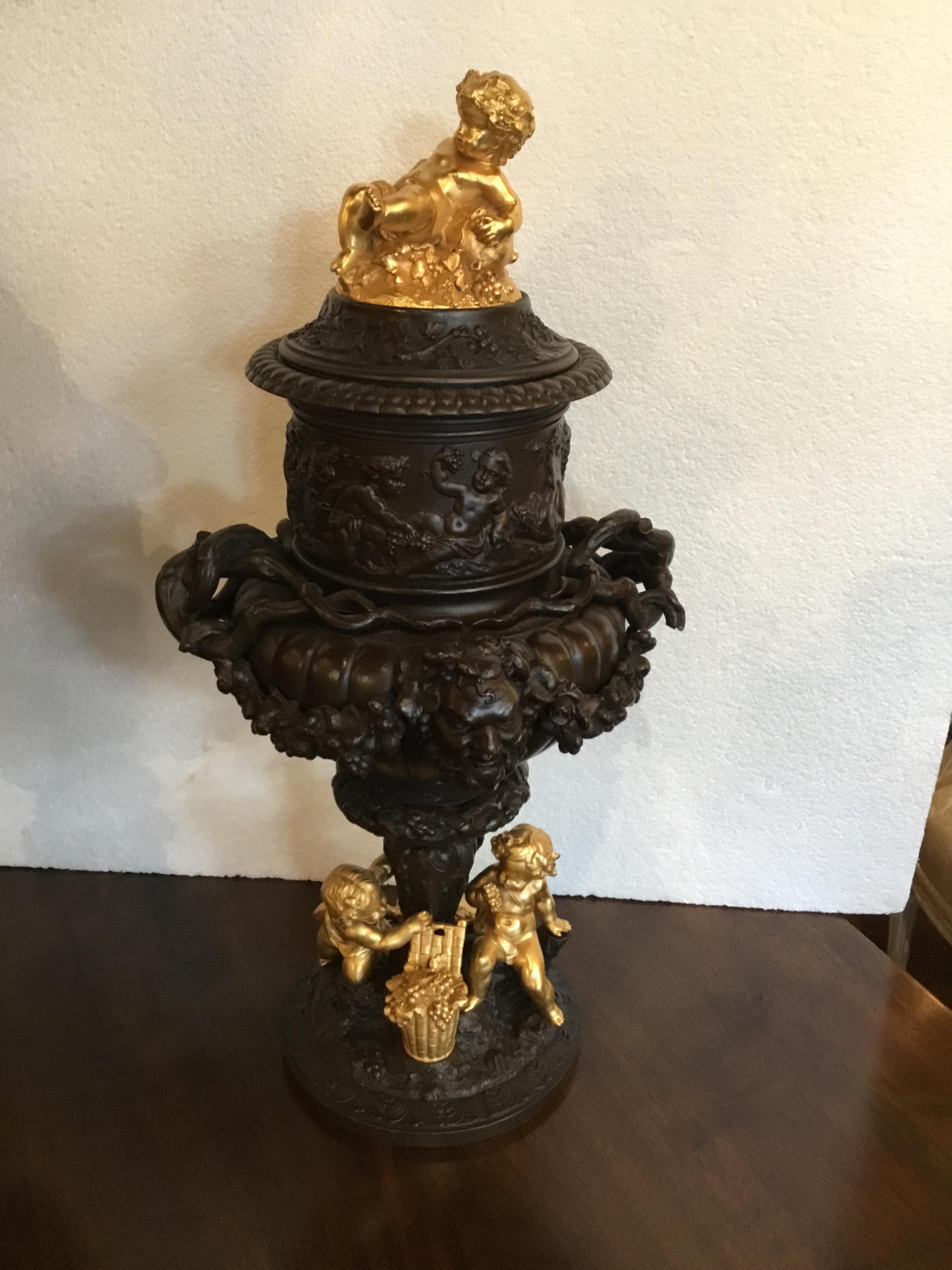 Pair of handsome bronze urns with a mask of baccantes centered on the
Front of the urns. Playful putti in gilt bronze decorate the cap and the
Bottom of these pieces. The putti are gathering grapes for their basket.
Floral and foliate designs