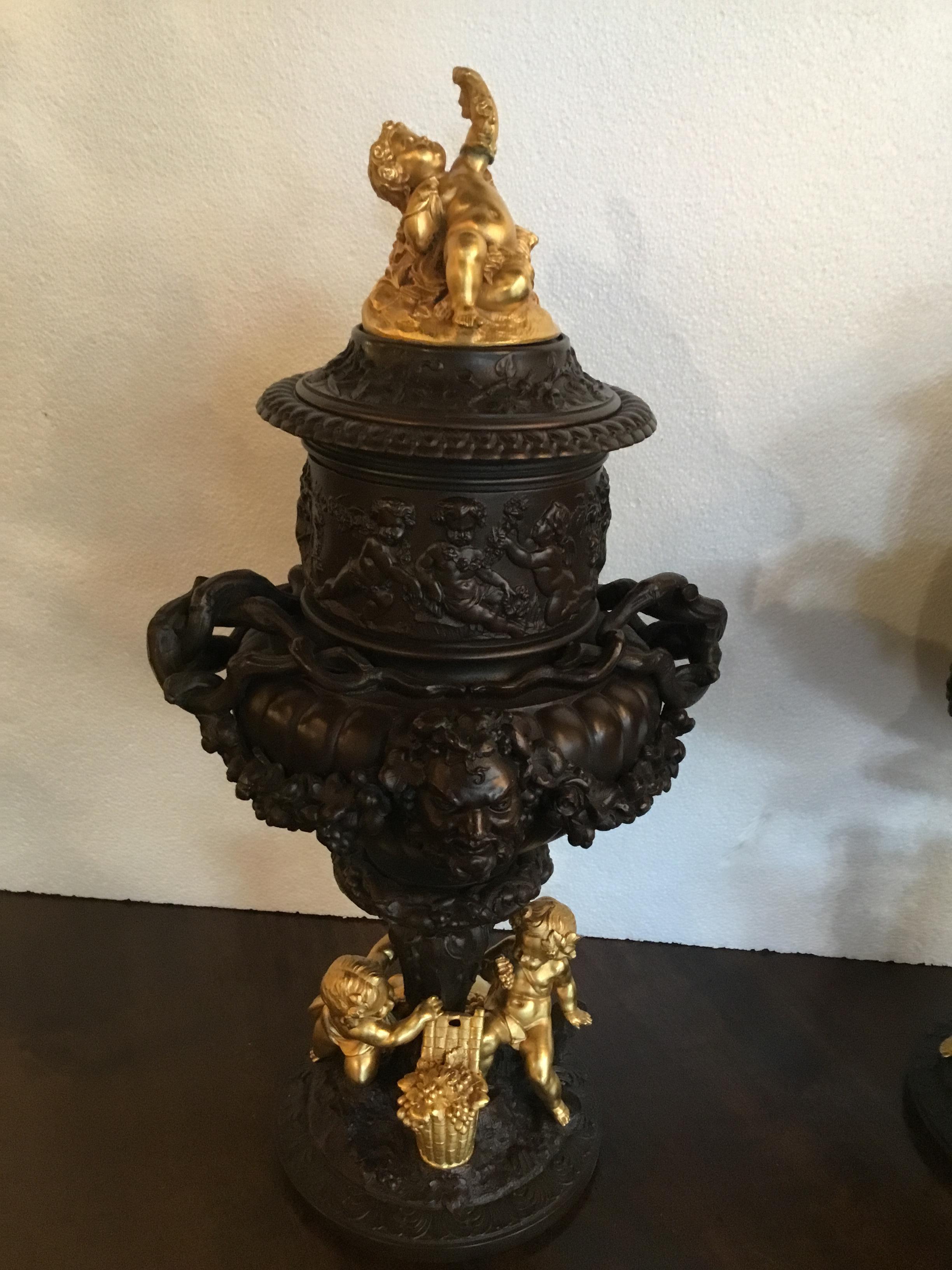 French Pair of Dark Patinated Bronze Urns with Gilt Bronze Putti Caps, Baccanal Mask