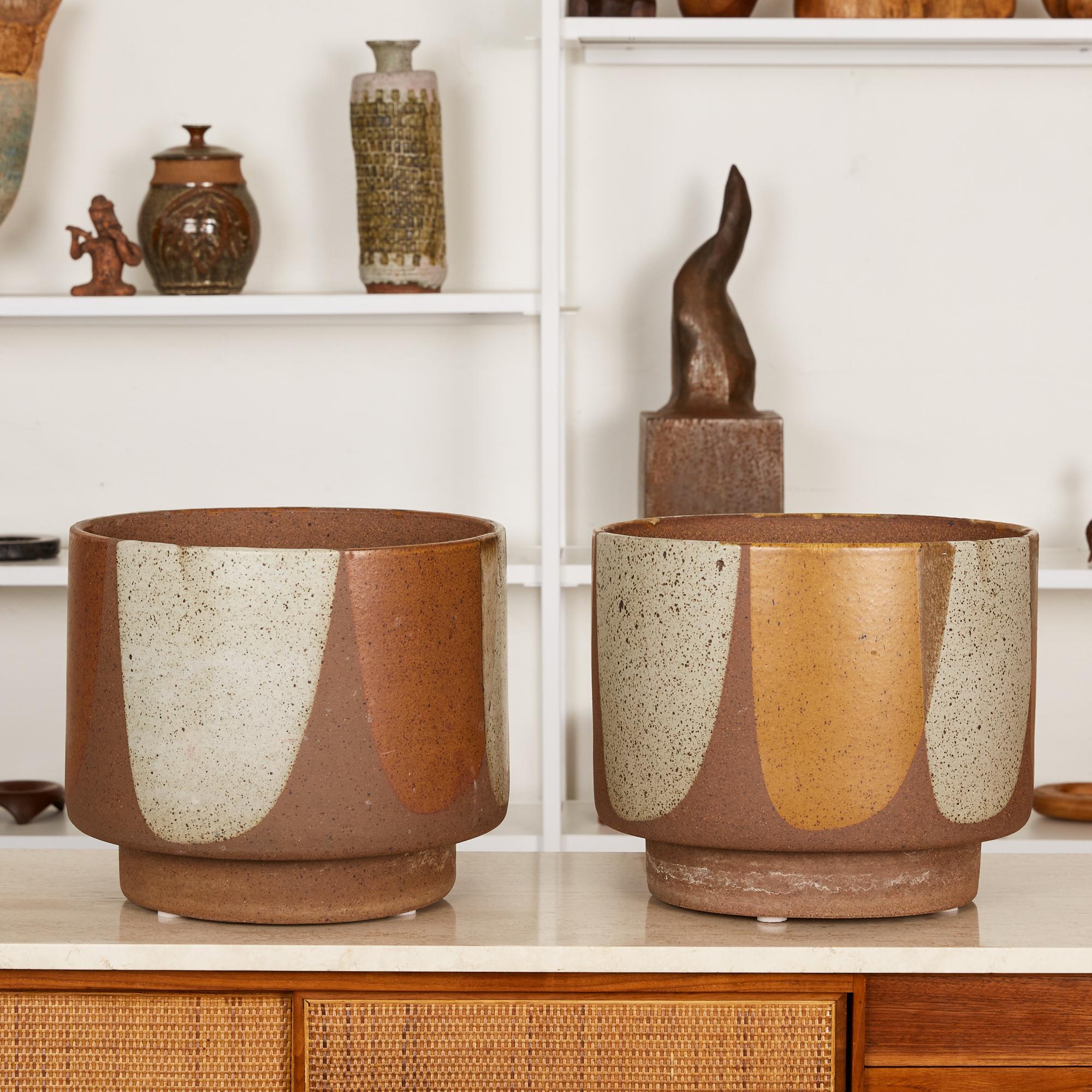 A pair of planters by Architectural Pottery with David Cressey’s Pro/Artisan “Flame Glaze.” The stoneware planters feature a round form with flat foot, a simple shape rendered dramatic by the white, brown, and orange painterly glaze that mimics