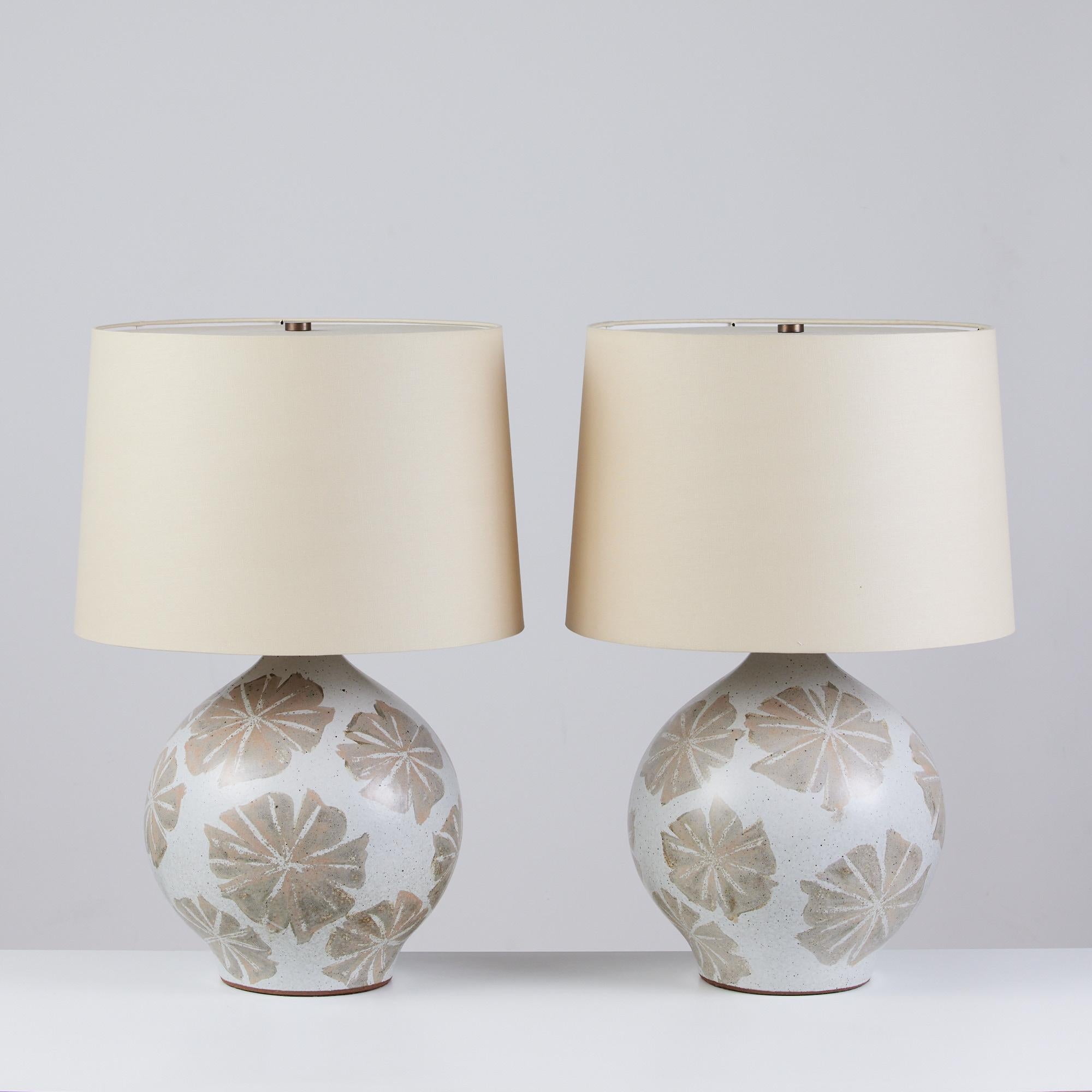 Pair of David Cressey Ceramic Lamps, USA, c.1960s. The wheel thrown ceramic lamps feature a speckled grayish blue colored glaze with applied floral detailing in a brown-gray tone. The newly rewired lamps feature new linen shades. The shades and