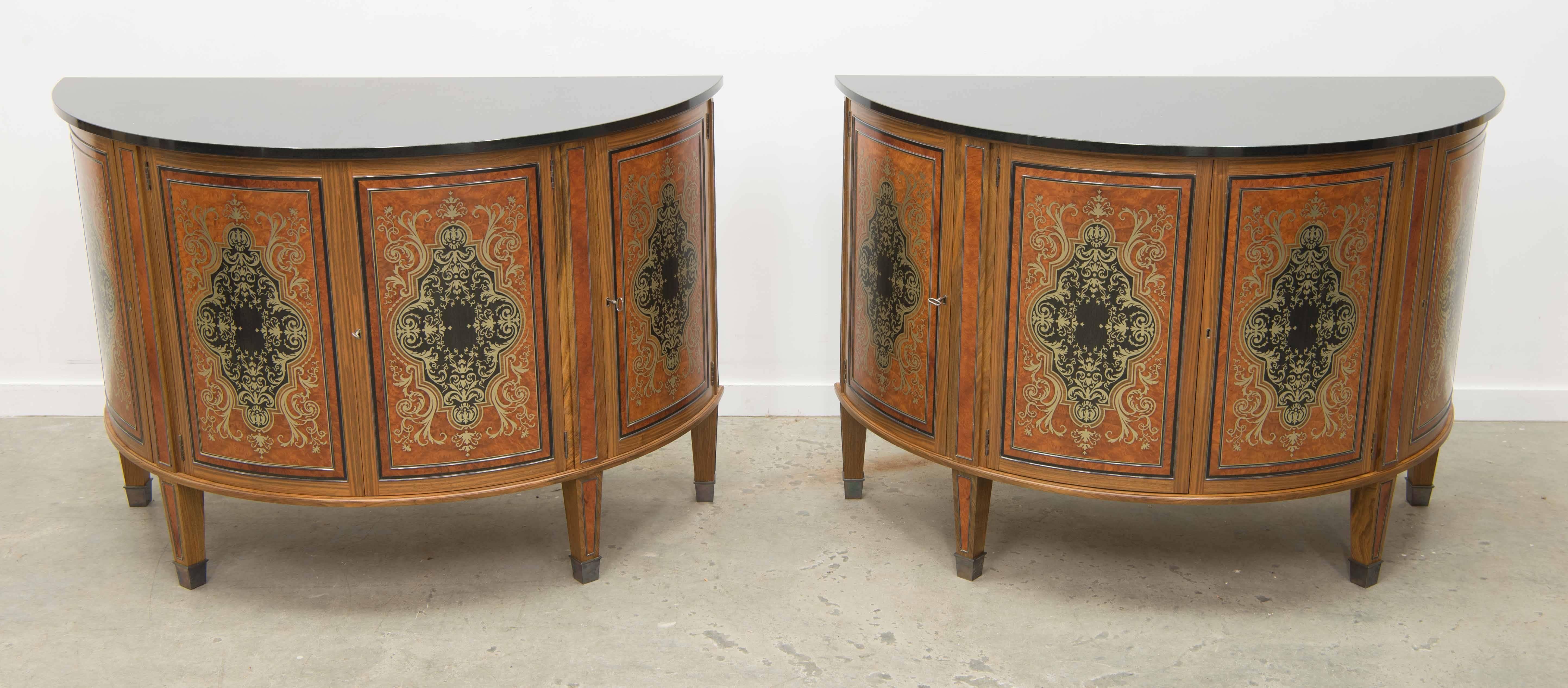 This is an extraordinary pair of David Linley commodes. 

They are an exact pair of demilune commodes with black marble top. They both have four doors with Boulle inlay in different kinds of wood and silver inlay. Inlay is made of English walnut,