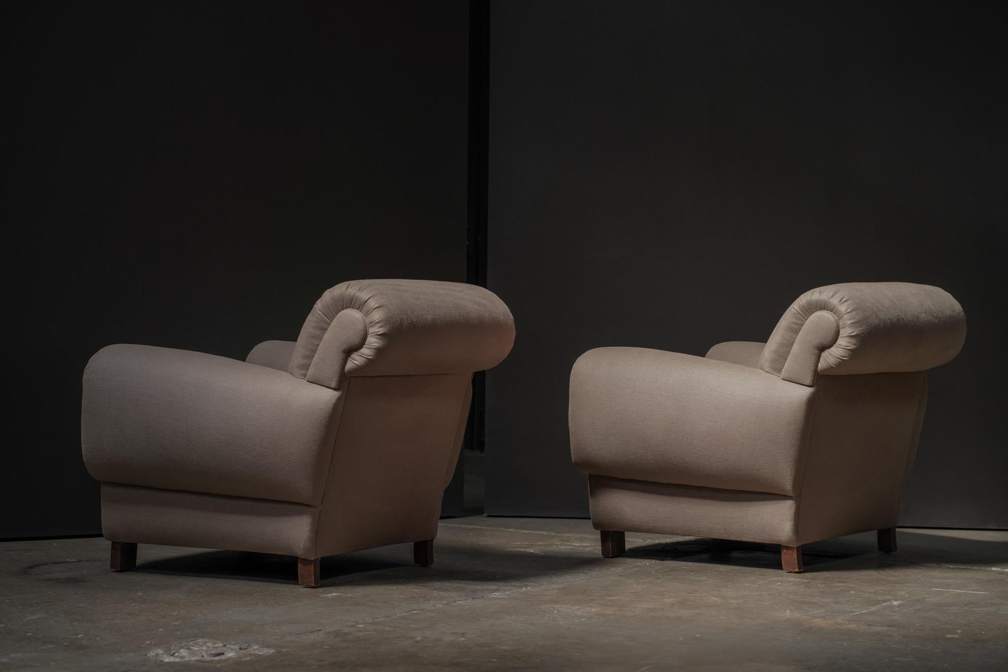A refined pair of Art Deco lounge chairs from France, featuring elegant pleated arm panels and newly upholstered in a soft, natural linen. Their sculptural form and tailored detailing lend timeless sophistication to any setting.