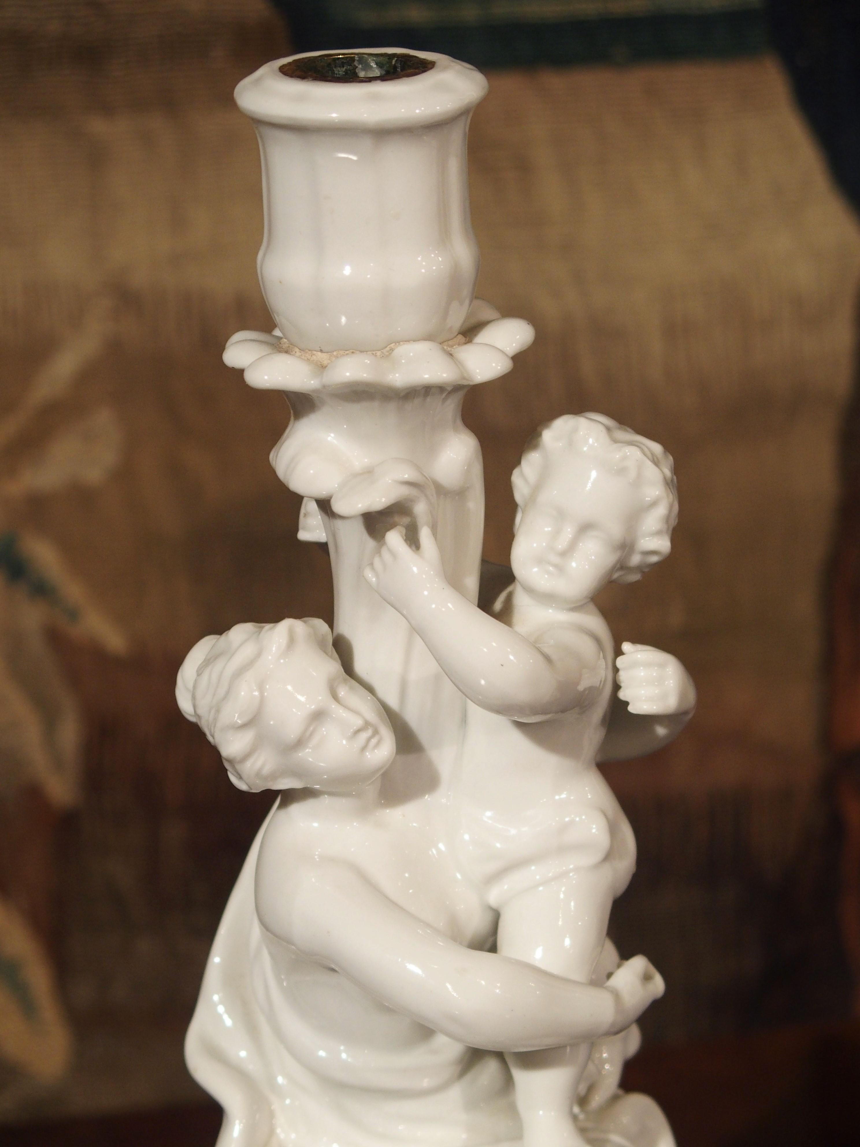 These charming candlesticks are just over one foot tall and feature classically inspired draped female figures holding up small cherubs. Each cherub grasps the top of the candleholder, which is in the form of a stylized stalk, while the bases are in