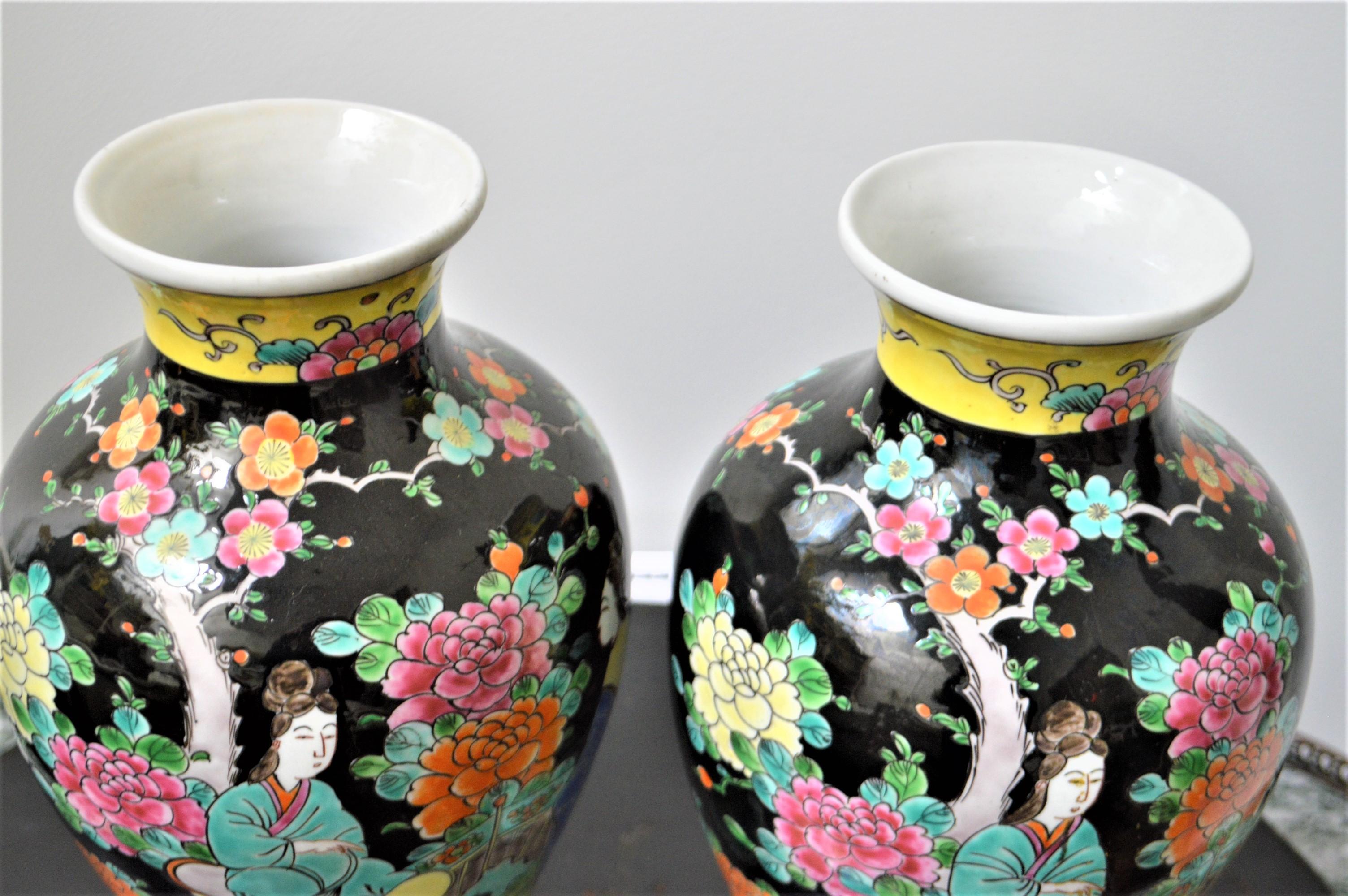Hand painted glazed porcelain vases on a black background showing two female figures in a garden setting. The colors are very attractive with beautiful pinks, orange, blue and green. There are slight differences in the rendering of each vases.