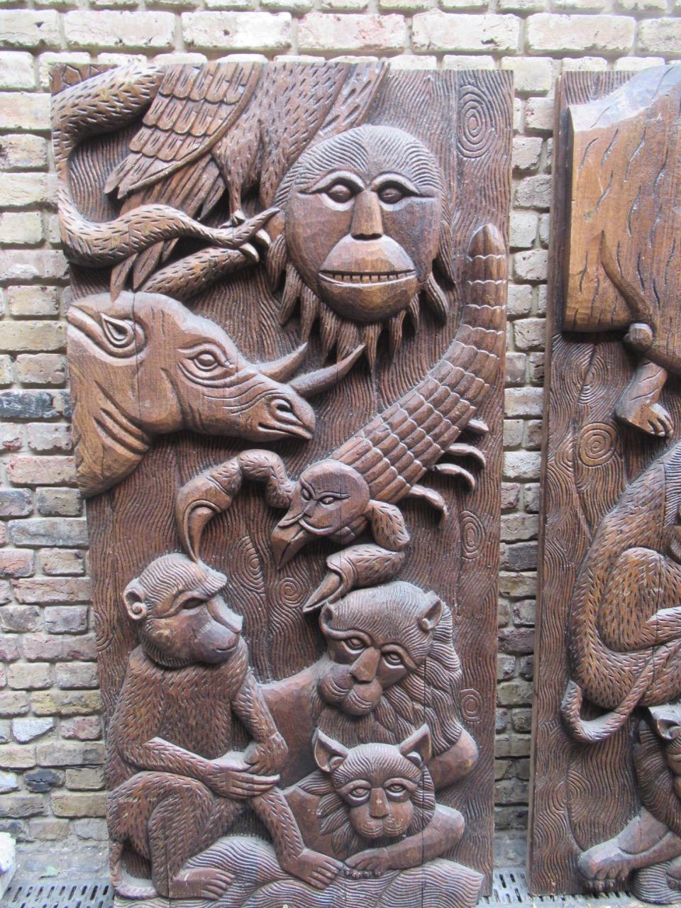 A pair of decorative teak wood panel sculptures carved in low relief, with monkeys, rhinos and other wild animals carved in relief. This beautiful pair of panels were created and stood in the historic Camden Stables market in London.