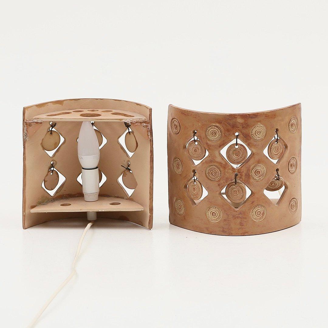 Incredible pair of ceramic sconces that can be plugged in or hardwired. Delicate hanging ceramic discs create beautiful shadows when the sconces are illuminated. Lovely shades of terracotta. 