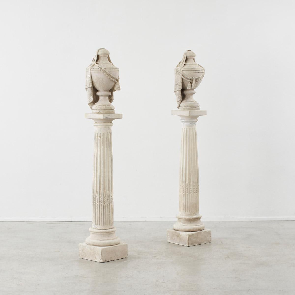 A decorative pair of classical antique French columns, with vessels fixed atop each plinth.