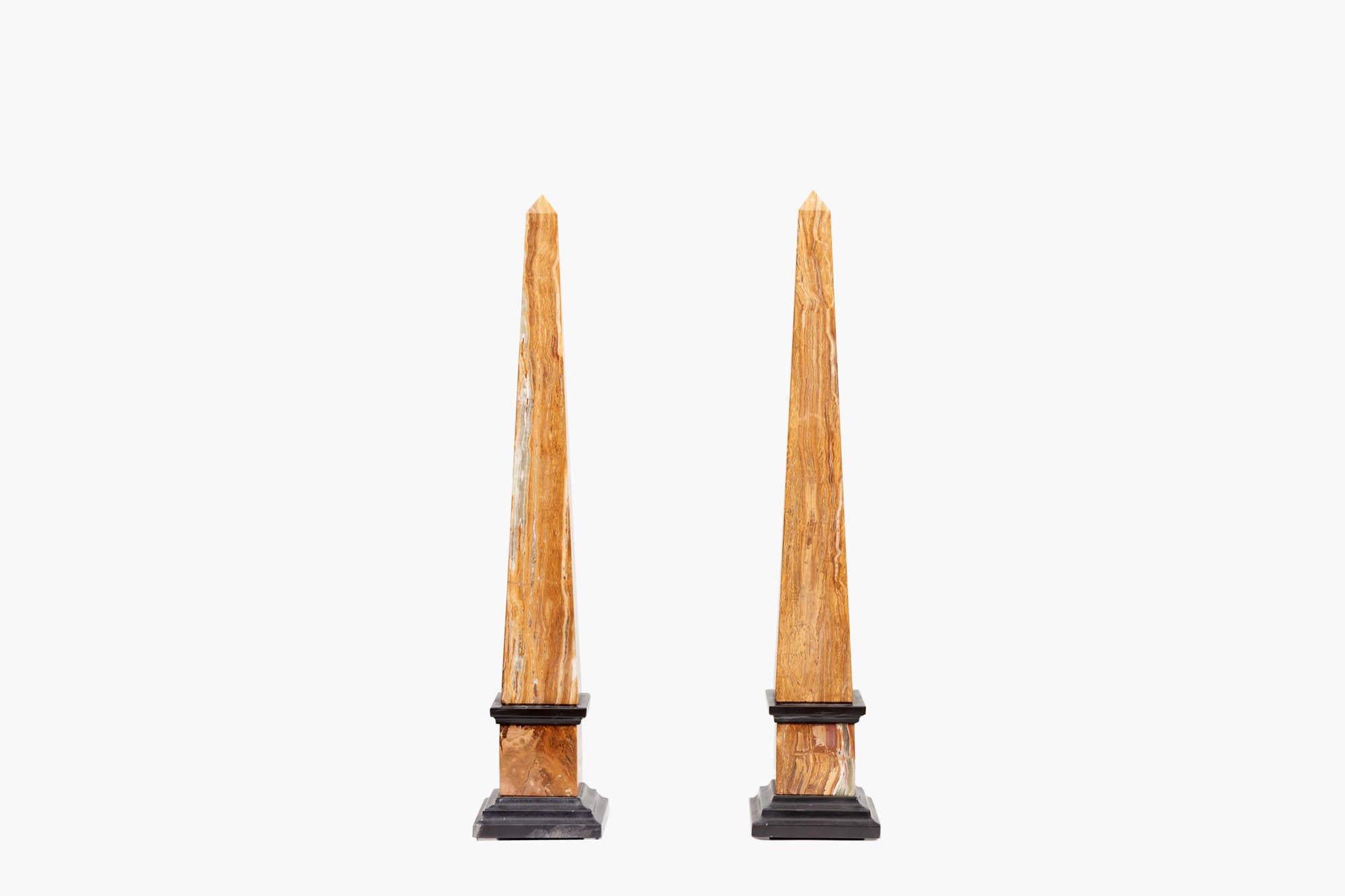 Pair of decorative Grand Tour Neoclassical-style obelisks dating from the late 19th/early 20th century. The tapering bodies are raised on square-stepped black marble bases and aprons that transition into contrasting rich yellow Italian marble