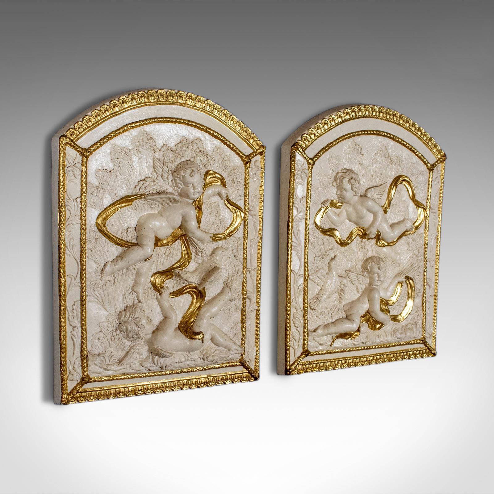 This is a pair of decorative panels, plaster reliefs of putti, or cherubs, highlighted in gold. Plaques dating to the late 20th century.

Beautifully detailed plaster panels
Profusely decorated and highlighted in gold
Classical scenes of putti,
