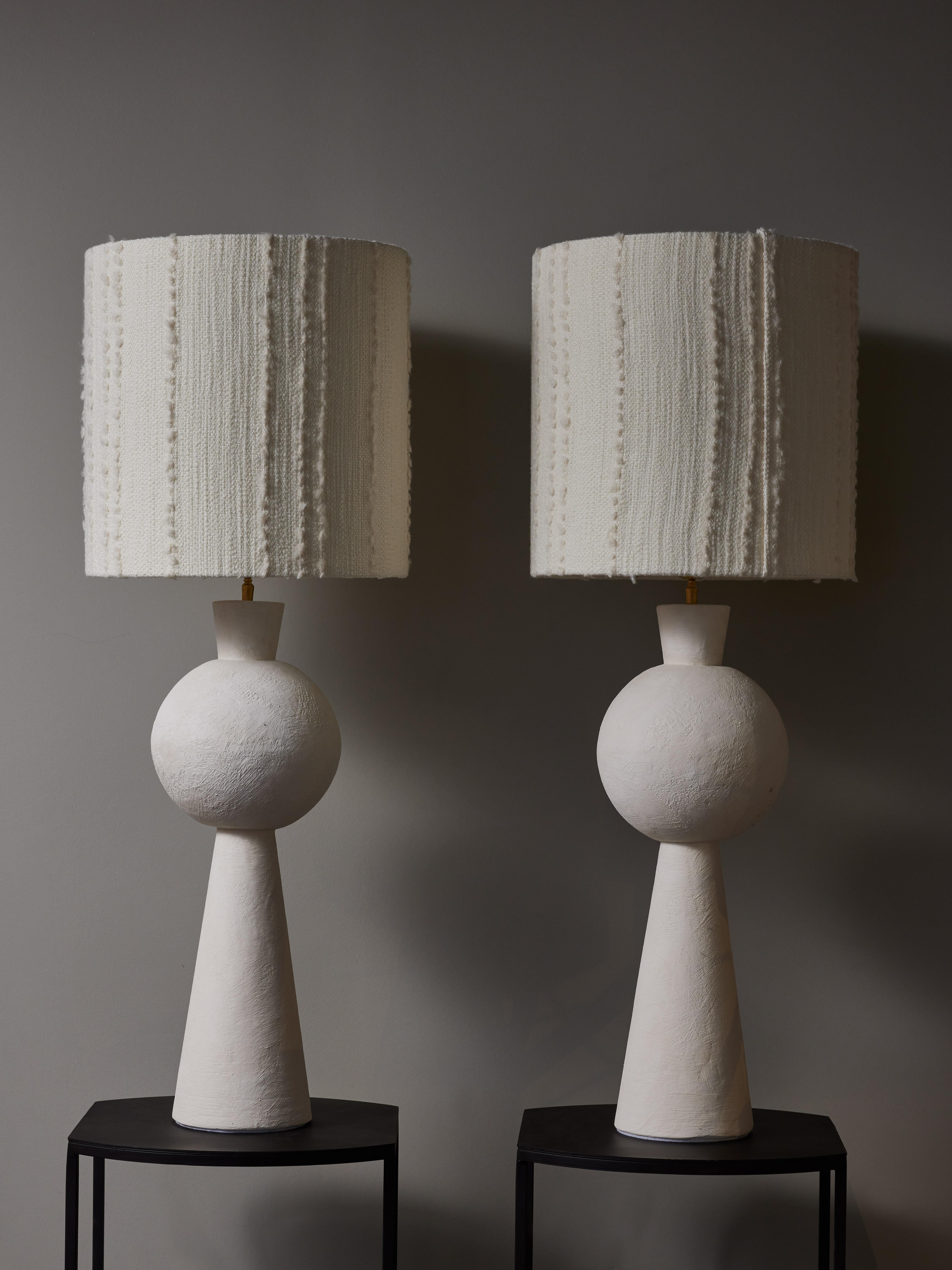 Ein Paar hohe Tischlampen aus Gips mit Messingbeschlägen, die mit modernen Lampenschirmen versehen sind.