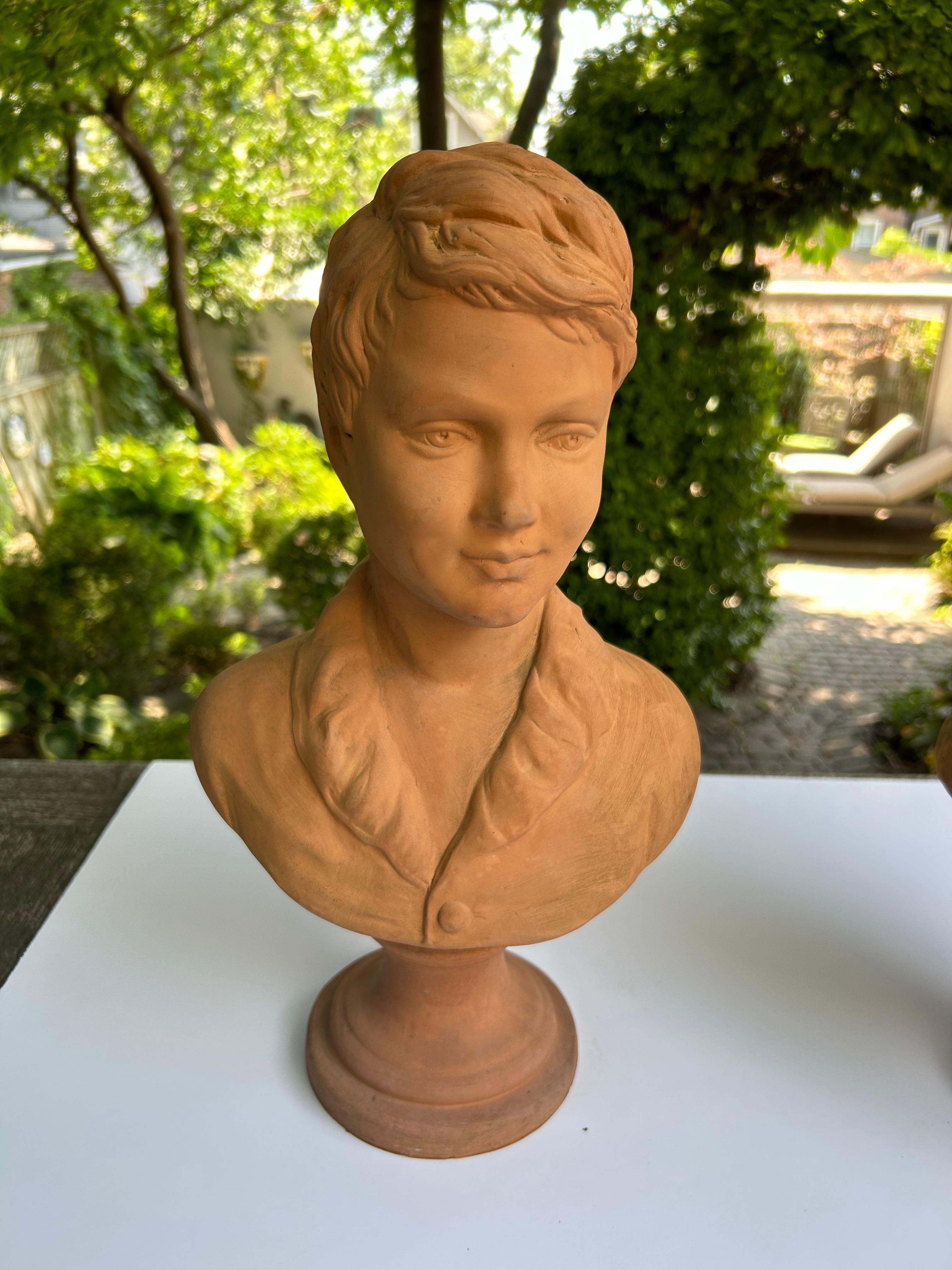 This is a wonderful pair of terracotta busts, depicting a boy and a girl. 20th century, most probably Italian.  Both raised on a circular base. Unsigned.
The bust of the young boy showcases a collared coat and that of the young girl a buttoned,