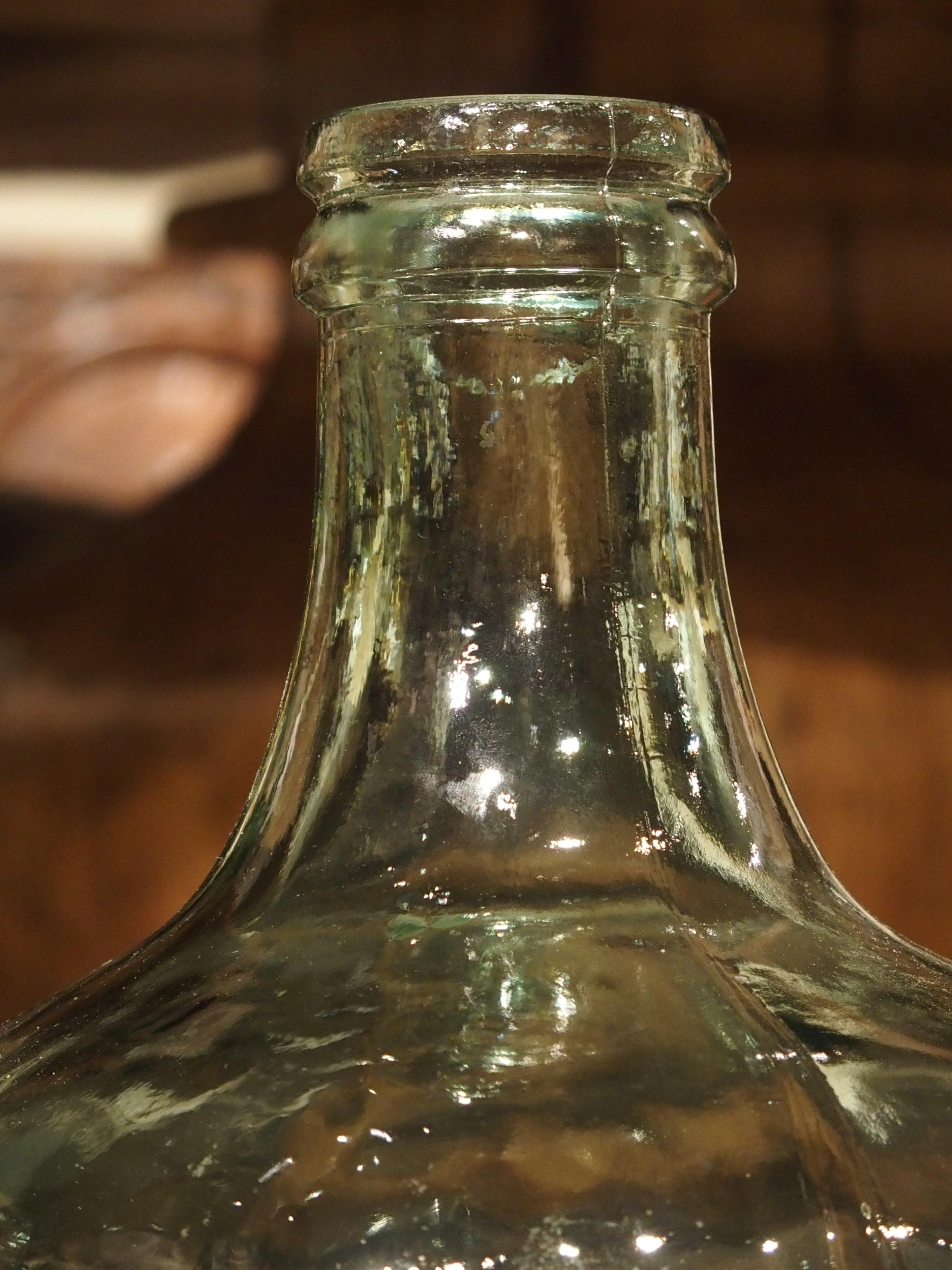 These continental European demijohns from the 20th century have green translucent glass that were embossed with a coat of arms above the word “Cabernet”. The wide mouths have an applied ring just below the mouth, and each was then finished to give a