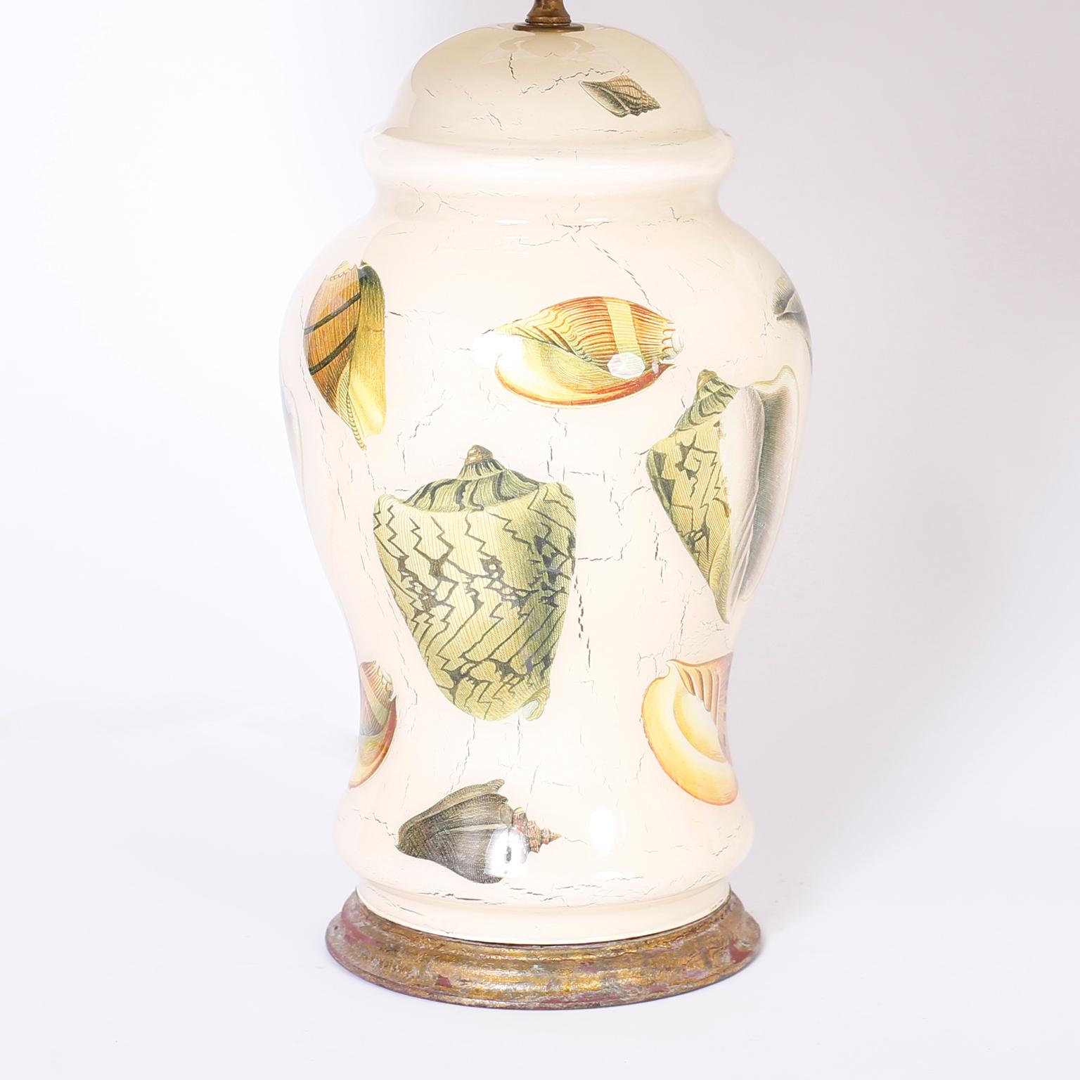 Midcentury pair of Italian table lamps with a Classic form and decorated with sea shells in a reverse decoupage technique against a cream colored background. Presented on distressed giltwood bases.