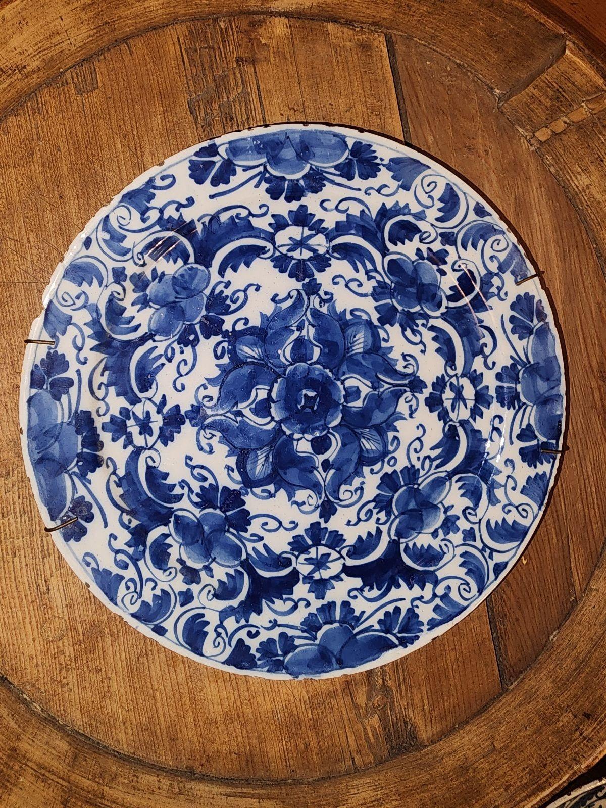 Una coppia di piatti delft blu scuro densamente decorati con un caleidoscopio di fiori e foglie dal centro ai bordi.  Conosciuto come modello De Grieksche A (la 