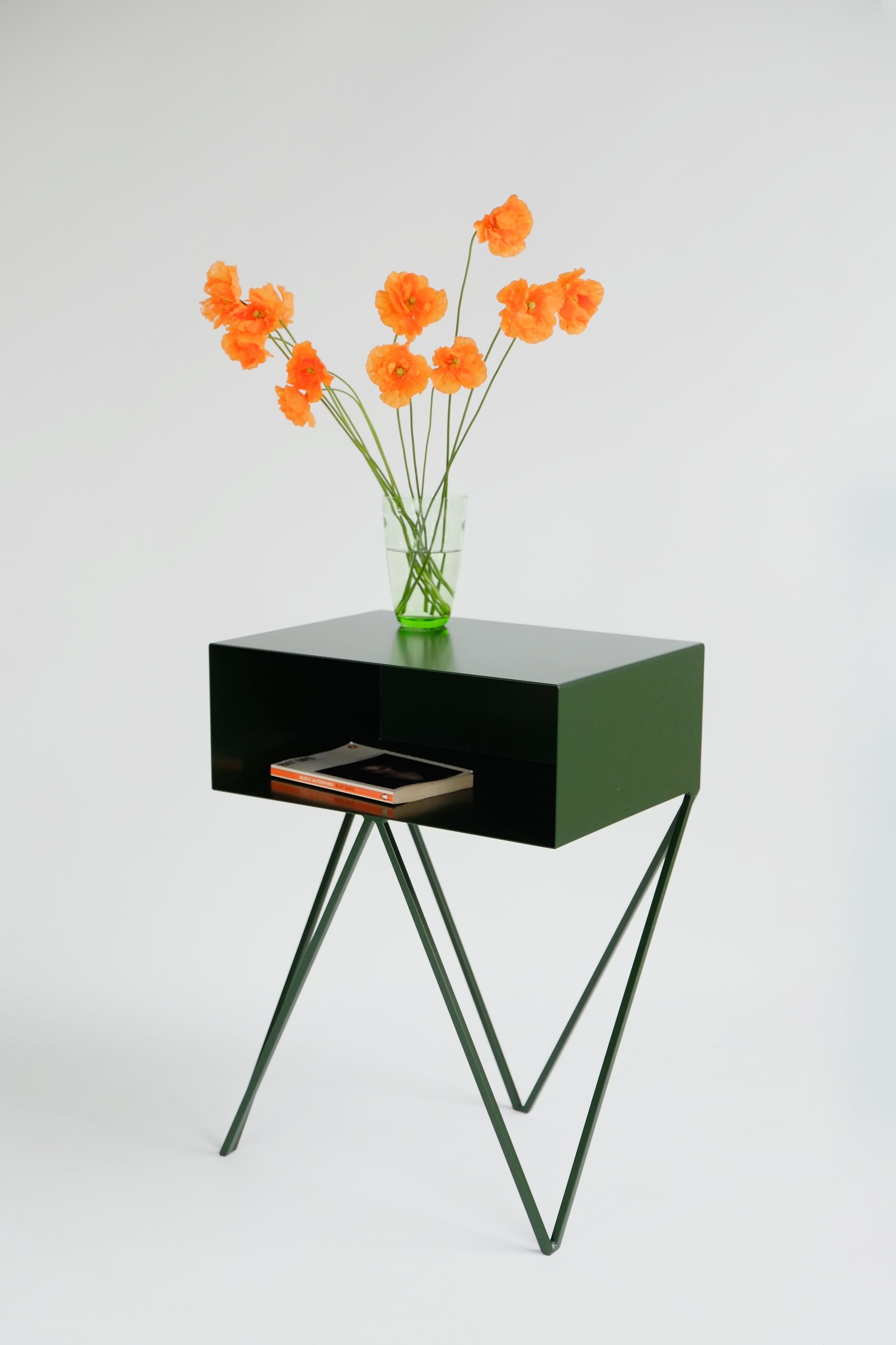 A pair of deep green Robot bedside tables. The side table features an open shelf on zig zag legs. A fun and functional design made of solid steel, powder-coated in deep green. The clean lines look great against period details as well as in modern